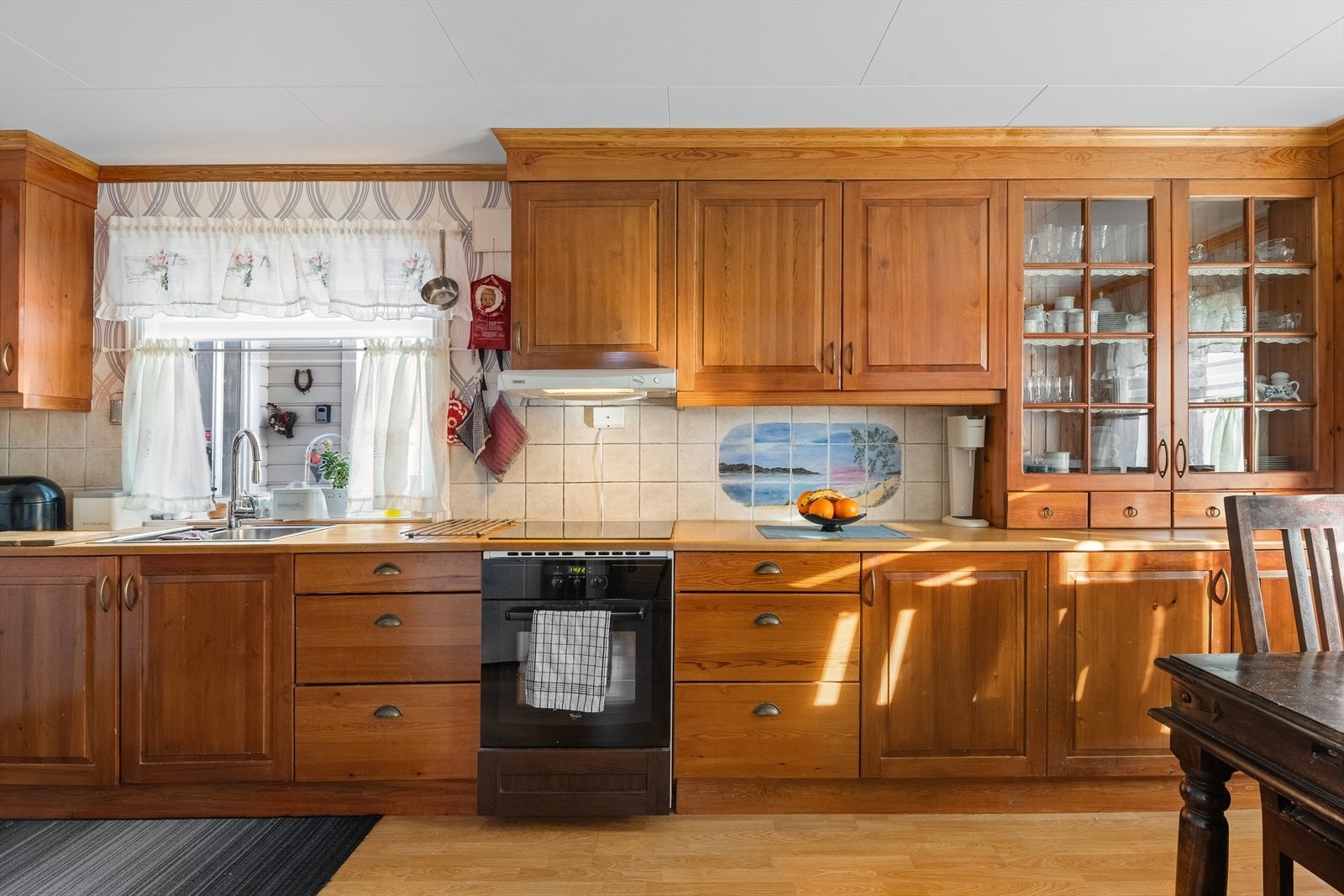 Kjøkkeninnredning med profilerte fronter, fliser over benk samt benkeplate av tre. Galleribilde