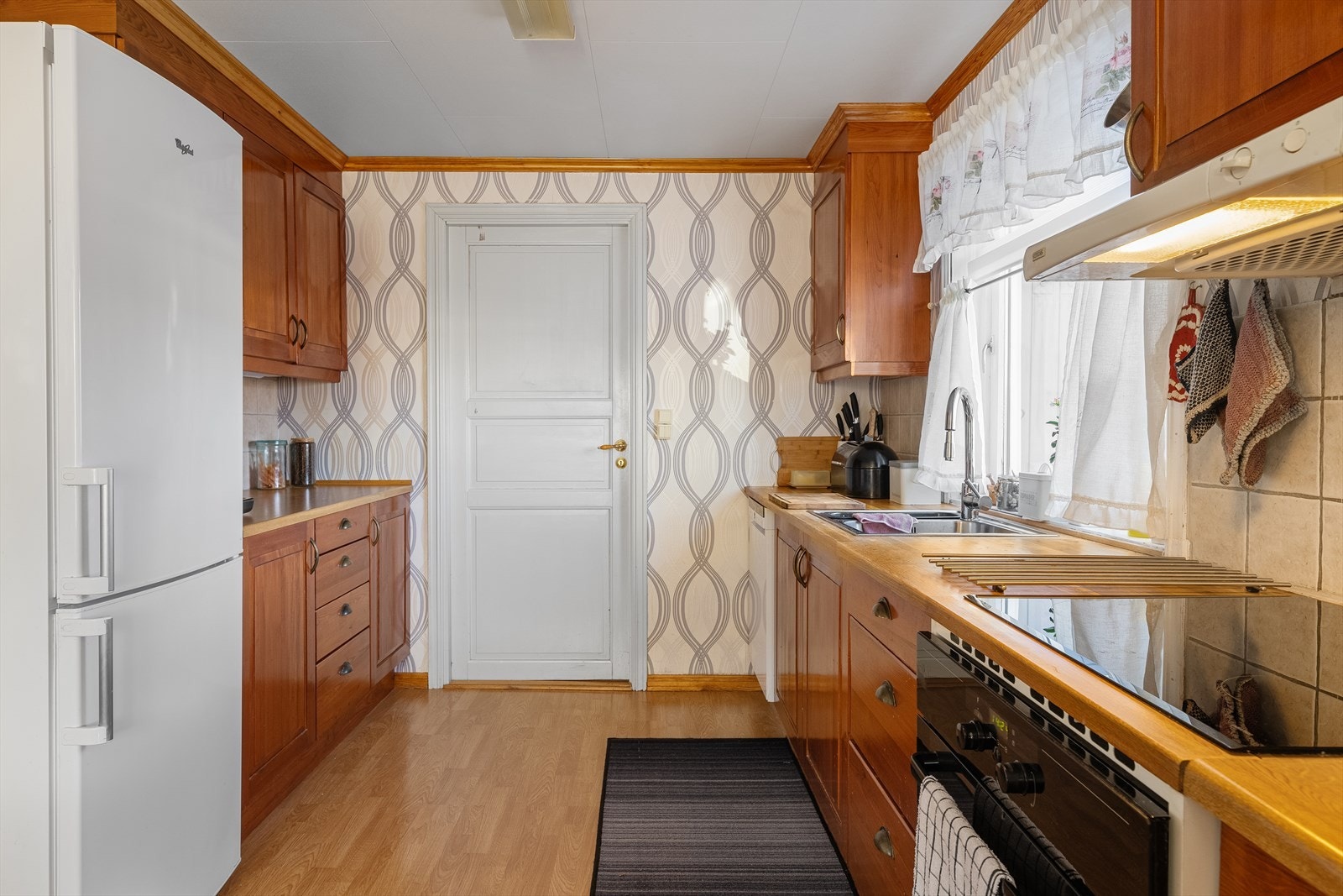 Kjøkken har parkett på gulv og tapetserte veggflater. Galleribilde