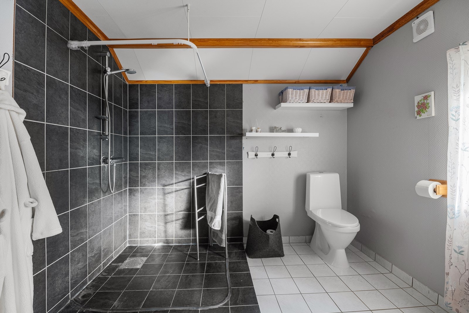 Badet er innredet med servant i skapinnredning, wc, dusj og opplegg for vaskemaskin. Galleribilde