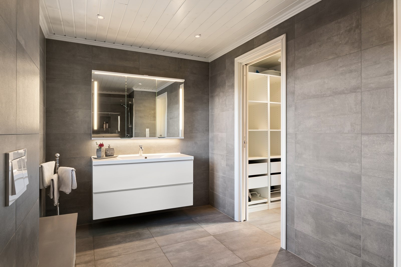 Badet inneholder baderomsinnredning med nedfelt vask, veggskap med speilfronter, vegghengt toalett og romslig dusj med glassvegg. Galleribilde