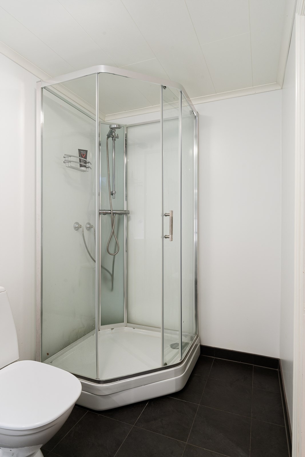 Badet er innredet med baderomsinnredning med nedfelt vask, toalett og dusjkabinett. Galleribilde