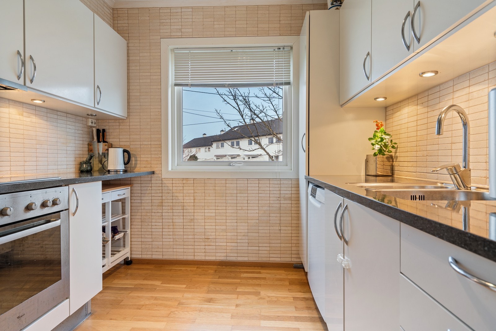 Tidløs, hvit kjøkkeninnredning innredet med komfyr, platetopp, oppvaskmaskin og frittstående kjøleskap. Rikelig med skap- og benkeplass på kjøkken! Galleribilde