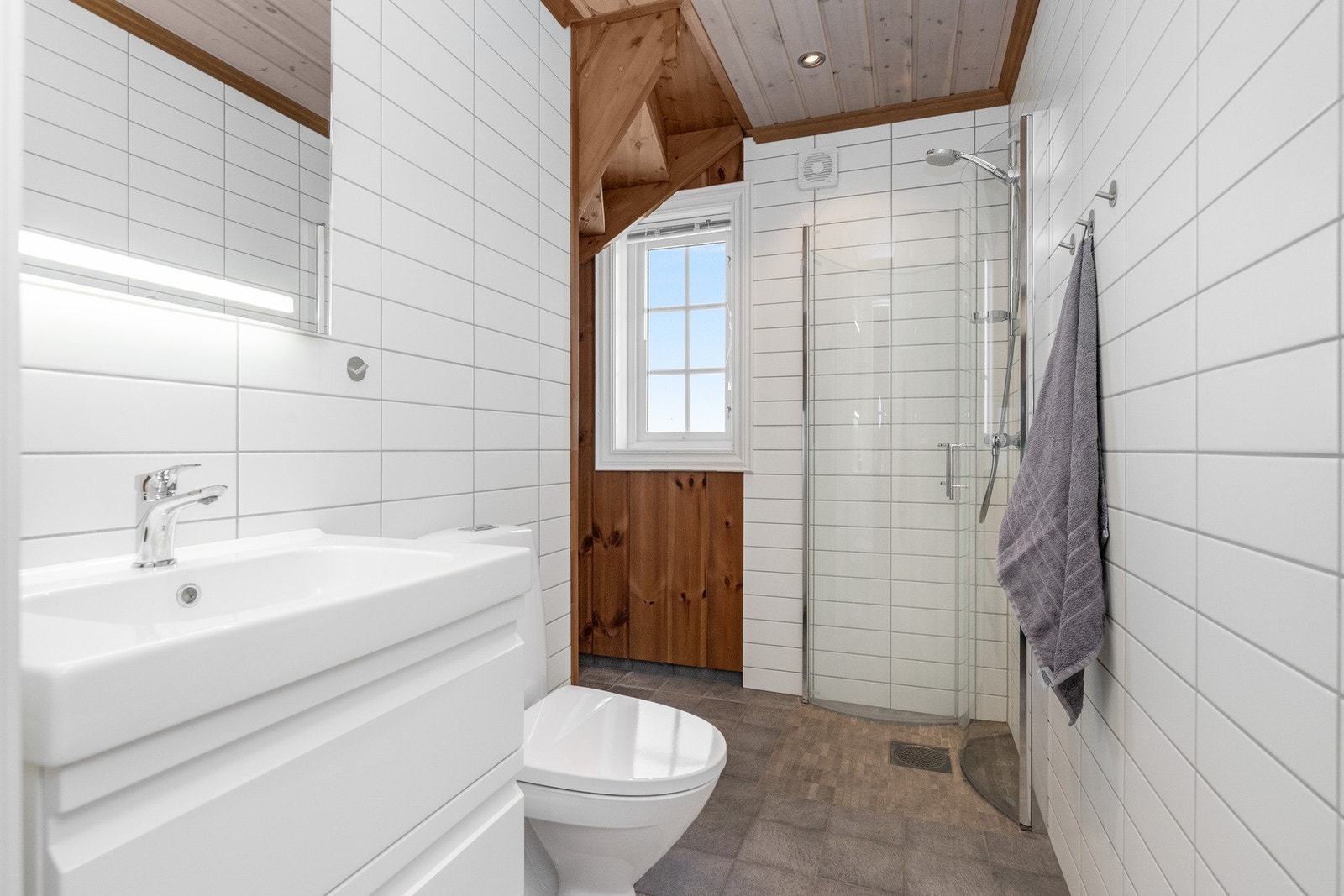 Lyse fliser på vegg og gulv. Varmekabler i gulv.
I hjørnet/under trappen er varmtvannstanken og teknisk installasjon plassert Galleribilde