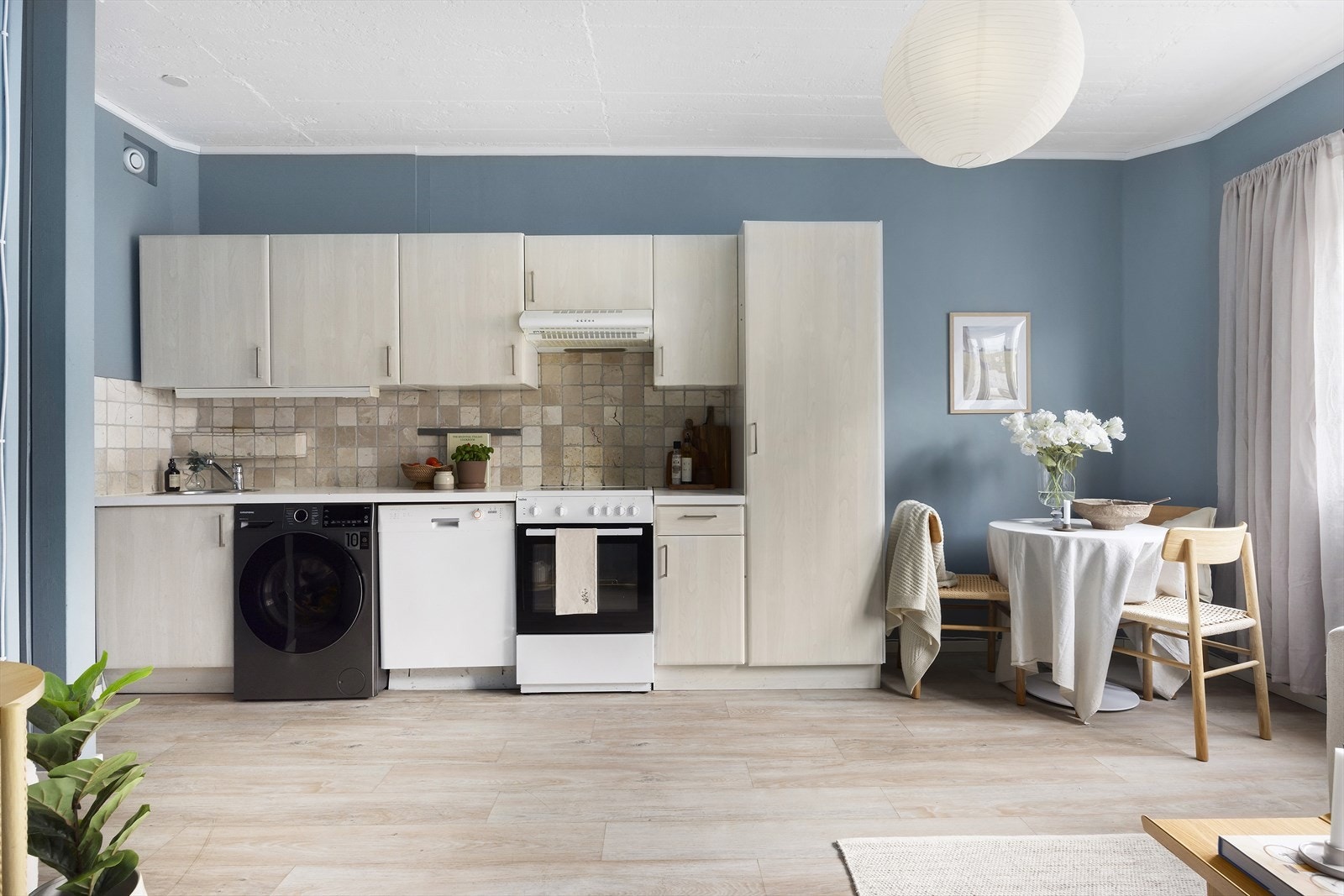 Pent kjøkken med slette fronter, nedfelt oppvaskkum og 1-grepsblandebatteri samt frittstående kjøl/frys, oppvaskmaskin, vaskemaskin og komfyr. Galleribilde