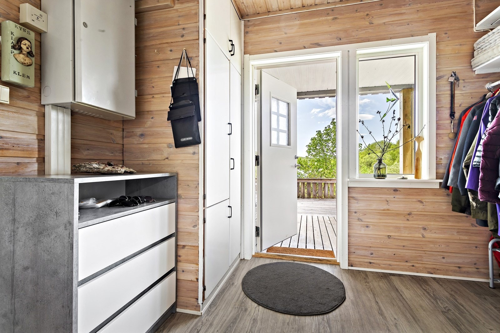 Det første og siste som møter deg i boligen er en romslig entrè med god plass til oppbevaring av sko og yttertøy. Fra ytterdøra kan du gå tørrskodd ut på den takoverbygde terrassen og nyte morgenkaffen. Galleribilde