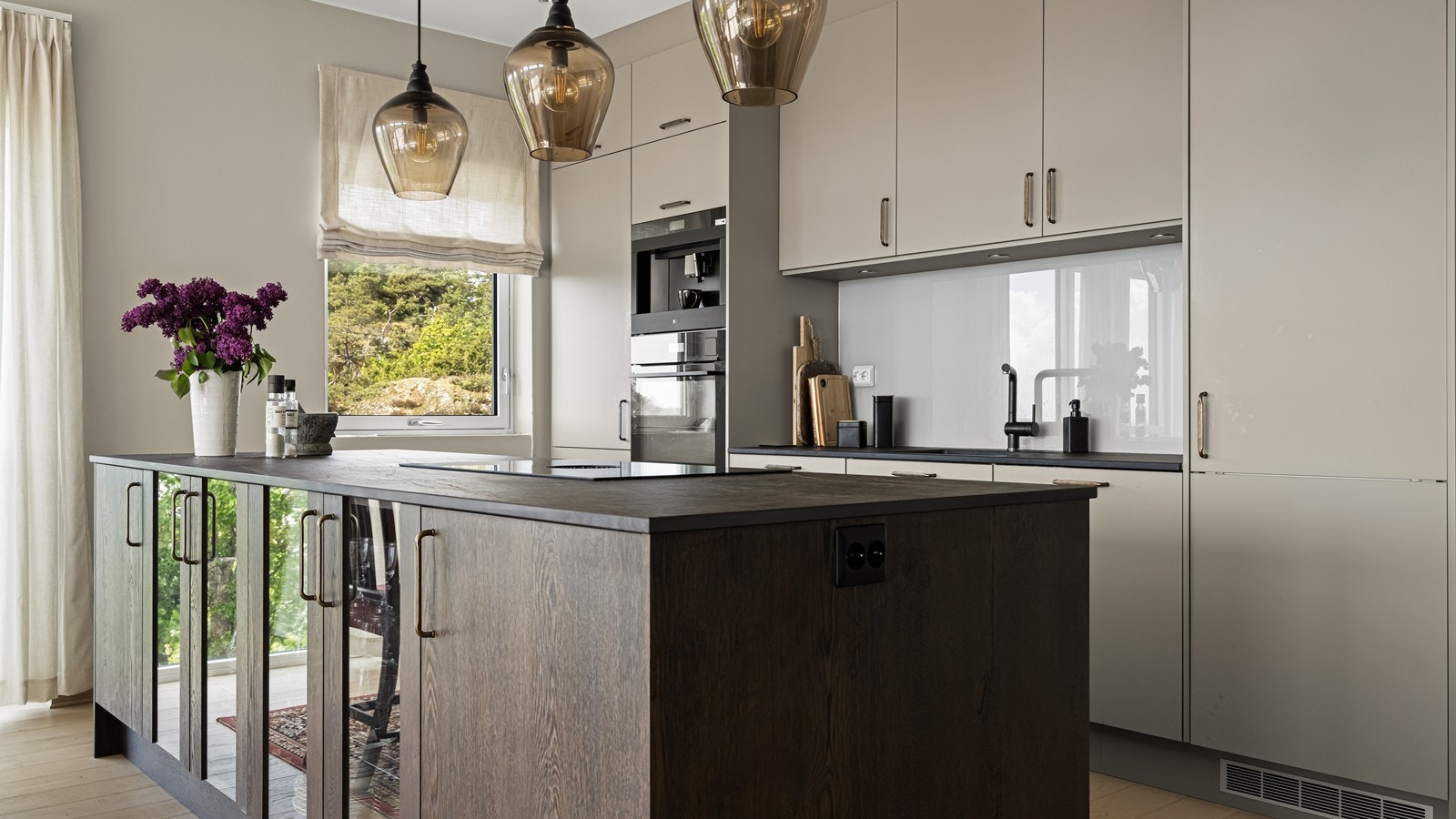 Kjøkkenøyen har gode løsninger med platetopp med integrert ventilator, vitrineskap i front og stikkontakt på siden Galleribilde