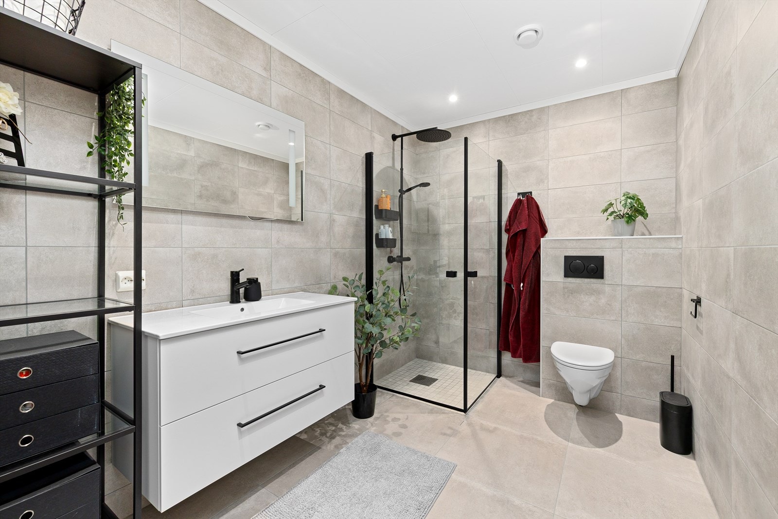 Stilrent, flislagt bad med elektriske varmekabler og tidsriktige sorte detaljer. Galleribilde