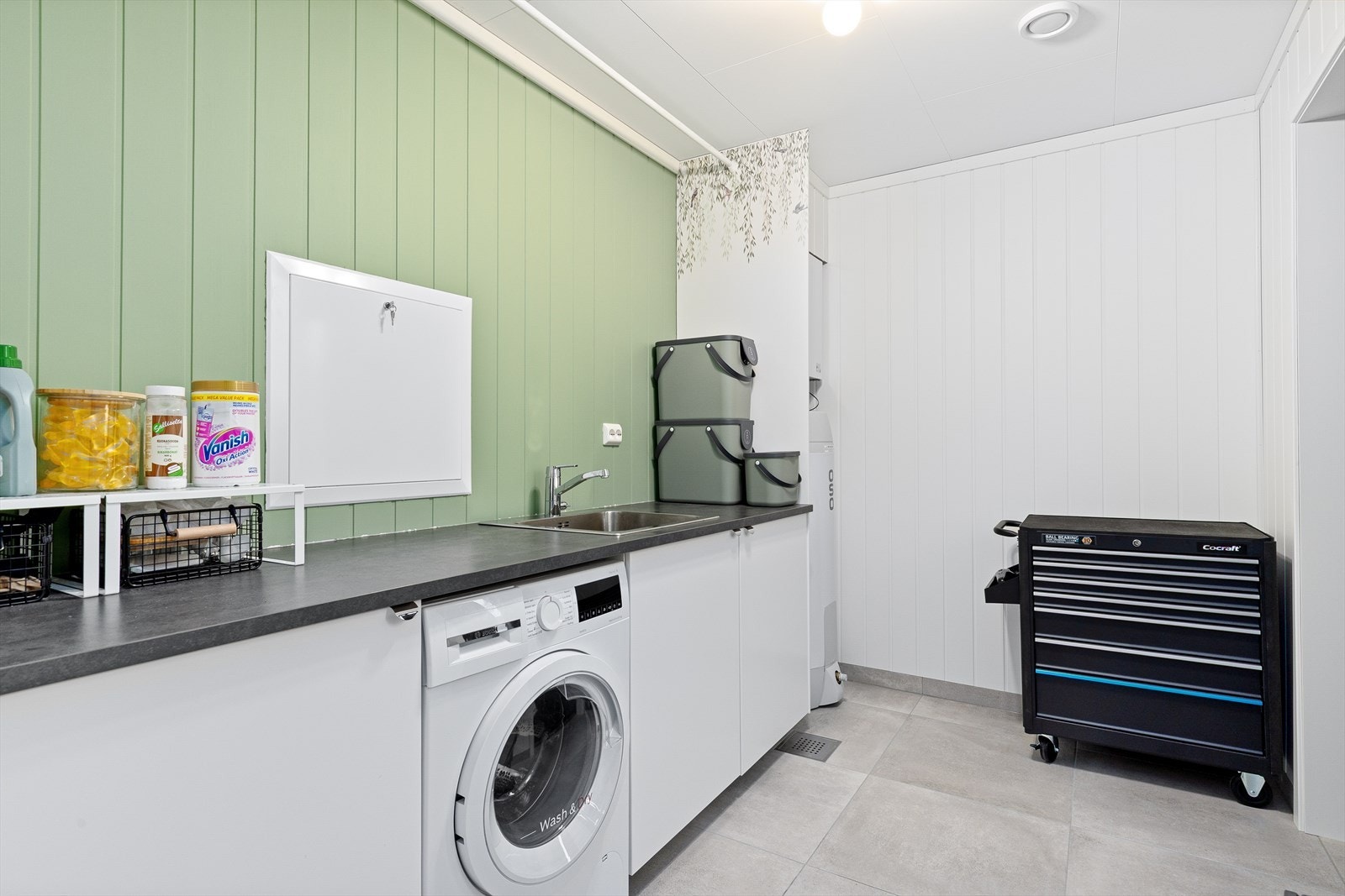 Praktisk vaskerom med oppbevaring i innredning og flislagt gulv med elektriske varmekabler. Galleribilde