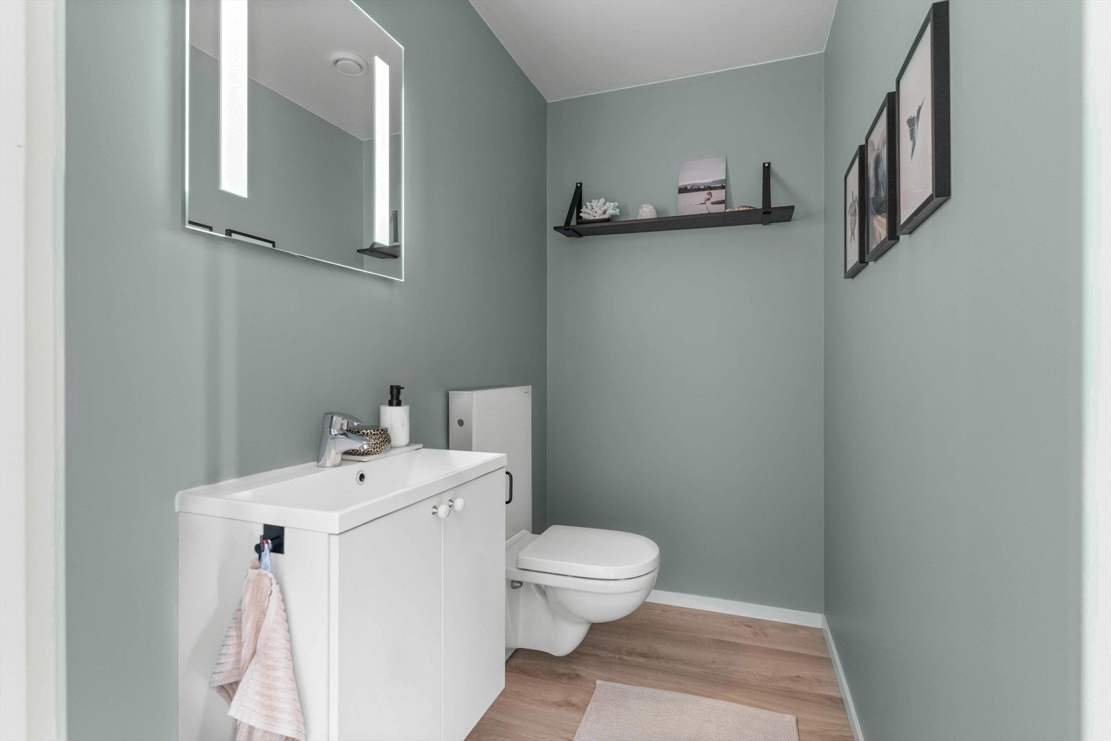 Det er inngang til et praktisk toalettrom. Her er det vegghengt toalett, samt servant med underskap og speil. Galleribilde