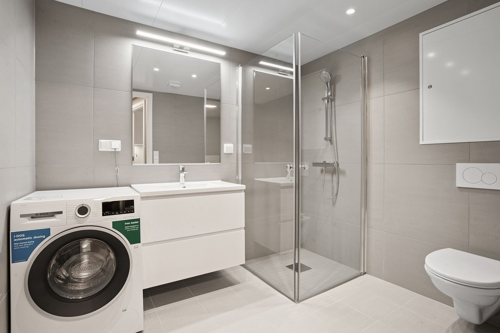 Delikat flislagt bad med vaskemaskin. Galleribilde