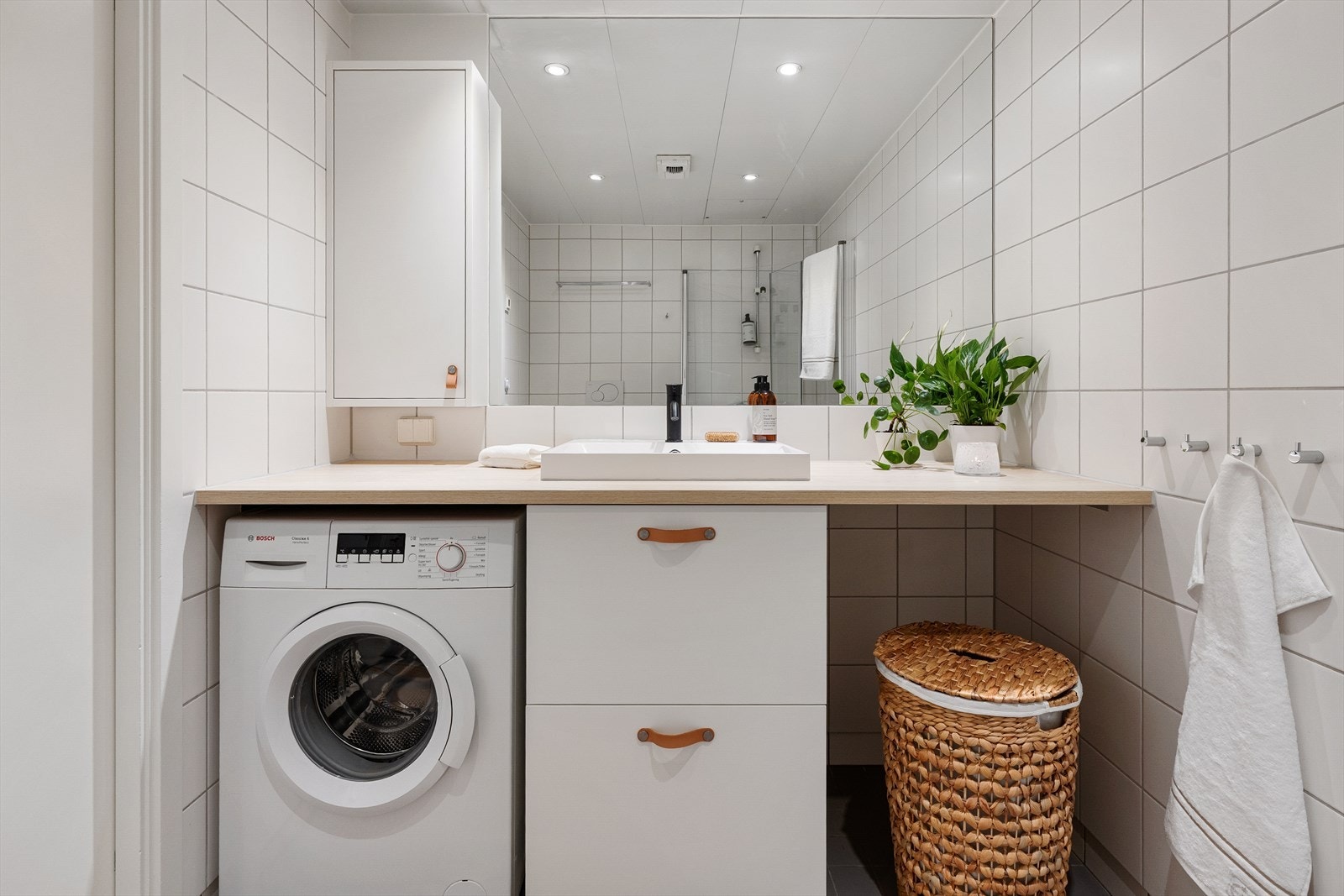 Innredning bestående av innfellbare dusjdører, mekanisk avtrekk, opplegg for vaskemaskin, servantskap, rørfordelingsskap, stoppekran og veggmontert wc. Galleribilde