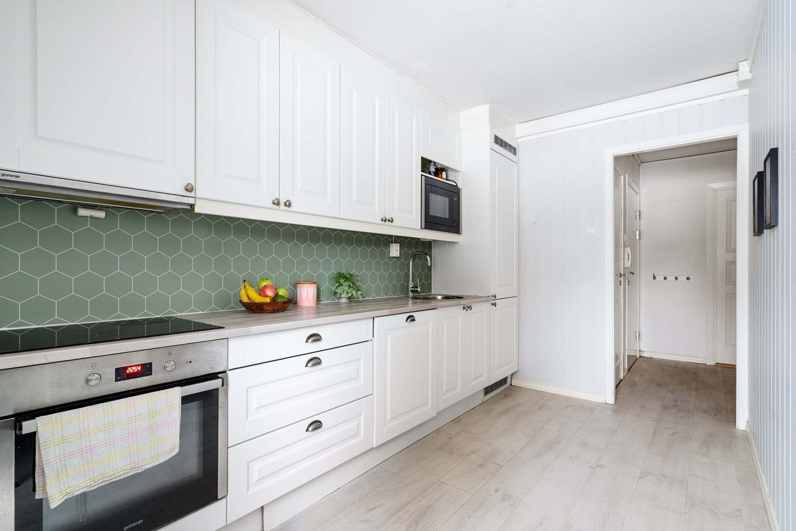 Lyst og innbydende kjøkken med god oppbevaringsplass i underskap samt takhøye overskap. Innredningen består av profilerte fronter og laminert benkeplate med nedfelt vask i rustfritt stål. Galleribilde