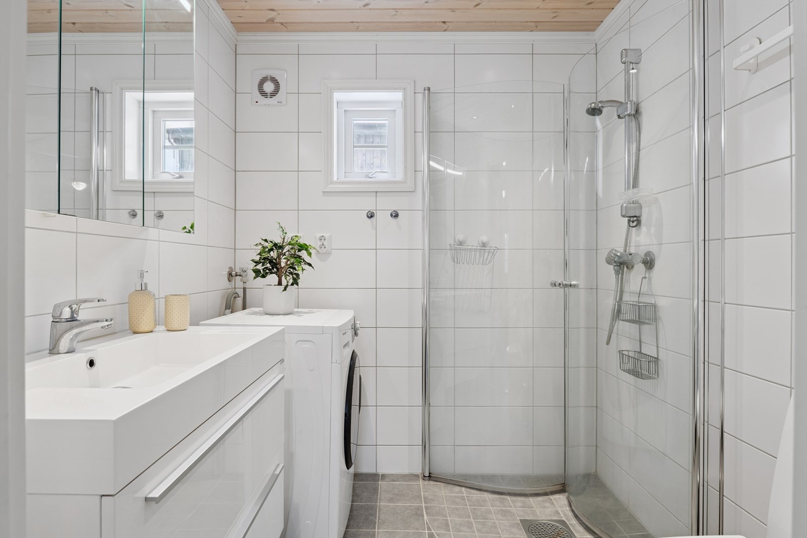 Helfliset bad i første etasje med dusjhjørne og opplegg for vaskemaskin. Galleribilde