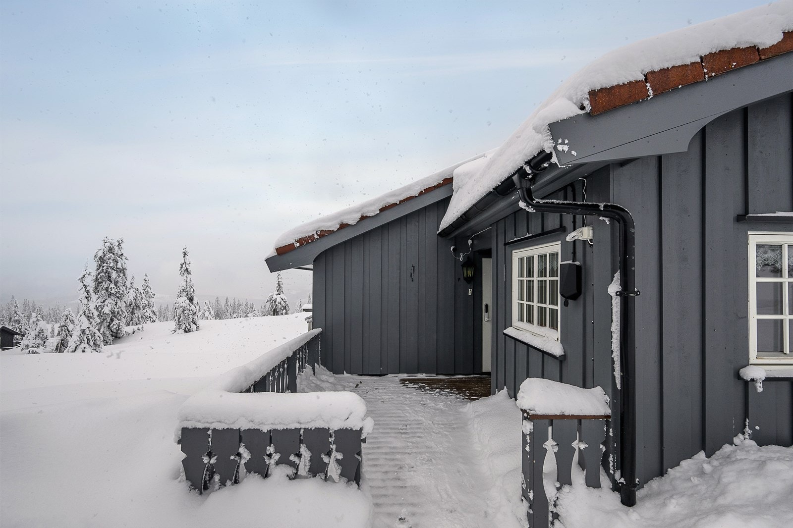 Åpen terrasse ved inngangspartiet. Det er installert elbillader på hytta. Galleribilde