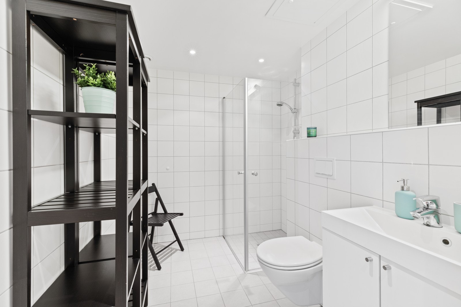 Badet er innredet med toalett, dusjhjøret og servant. Det er vaskemaskin i gang. Galleribilde