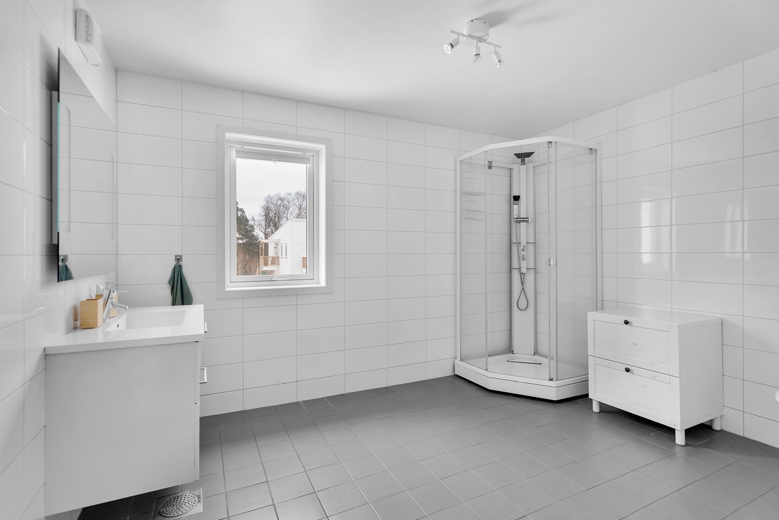 Bad 2.etg med flis på gulv og vegg, varme i gulv, dusjkabinett, vegghengt toalett og servant med underskap. Galleribilde