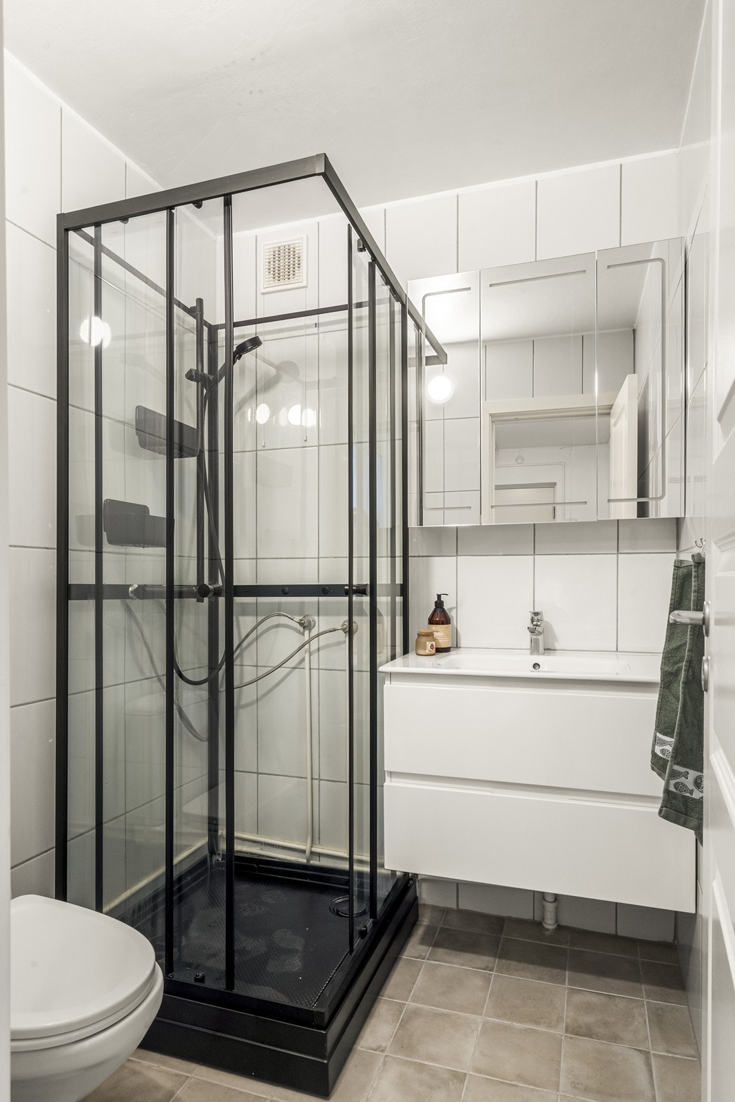 Badet er utstyrt med et moderne dusjkabinett med sorte profiler. Galleribilde