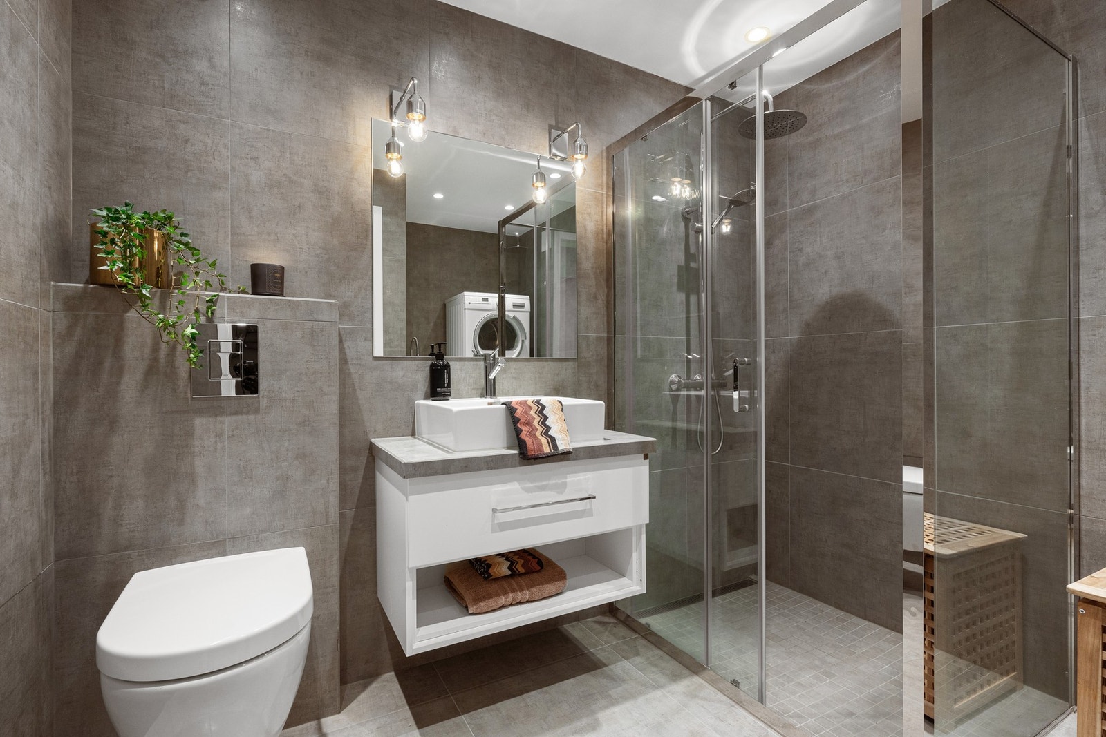 Baderommet er flislagt med varme i gulv og flislagte vegger, nedsenket himling med downlights og moderne innredning. Galleribilde