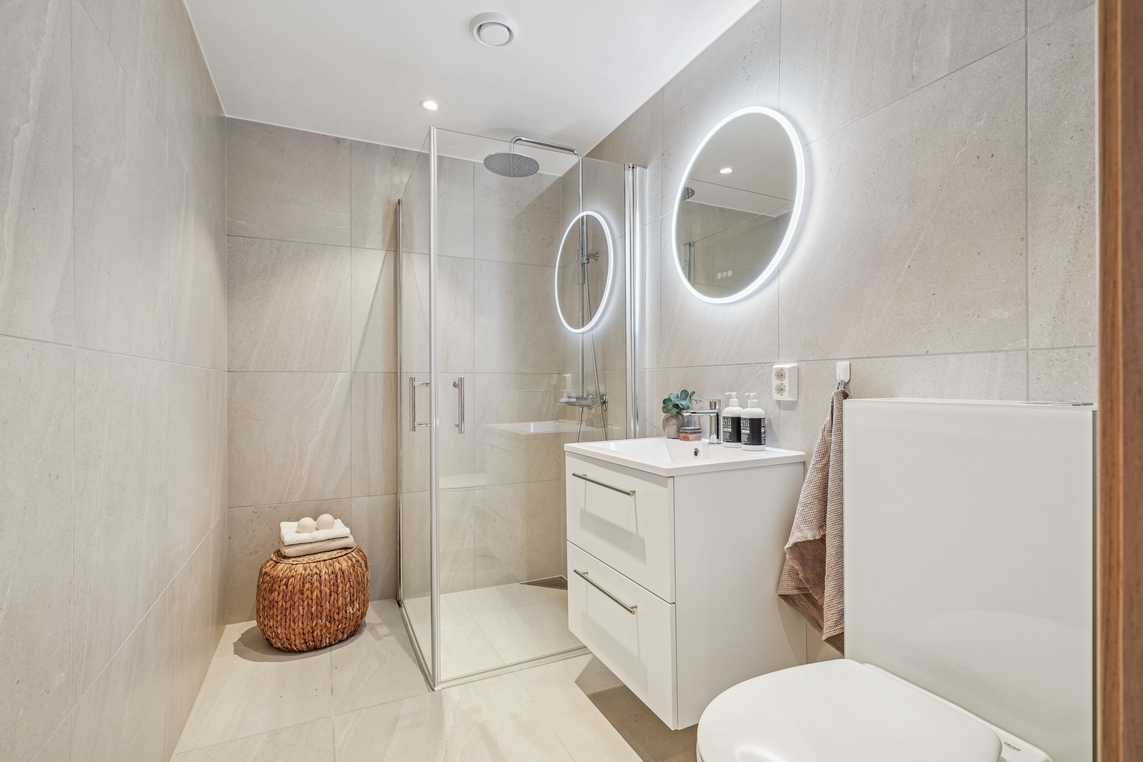 Gjestebadet er helfliset i delikate 60 x 60 fliser og har elektriske varmekabler i gulvet. Innredet med vegghengt toalett og dusjhjørne med regnfallsdusj - Galleribilde