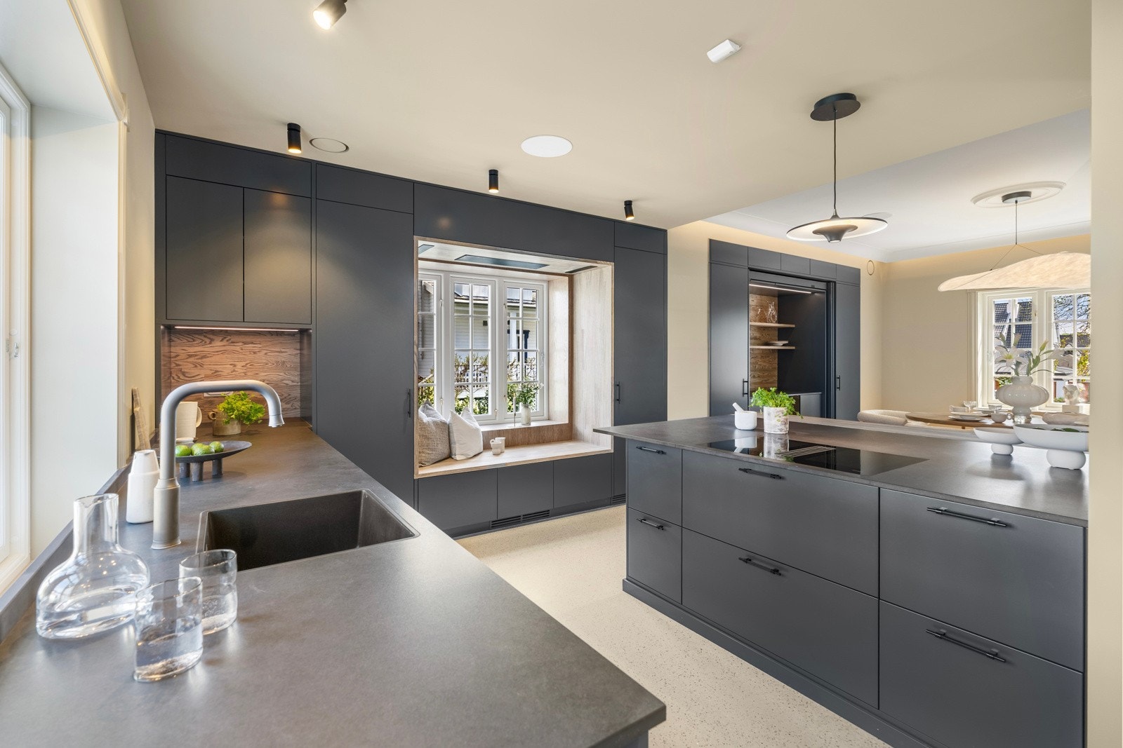 Vaskekummen i kompositt er underlimt i benken under vinduet, mens kjøkkenøya har planlimt induksjonstopp med innebygd ventiltaltor. Galleribilde