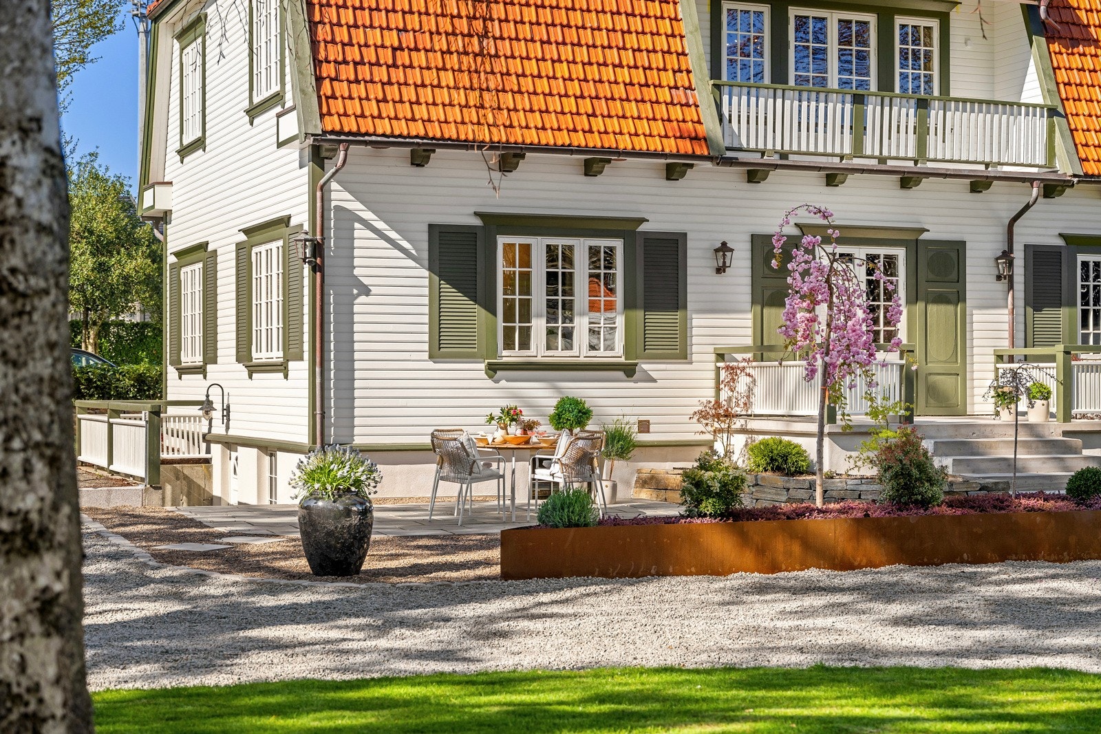 Mansardtaket er tekket i rød takstein, som skaper en komplementærkontrast til det grønne, og fasaden er i hvitmalt, liggende kledning med grønne konsoller mot gesims. Galleribilde