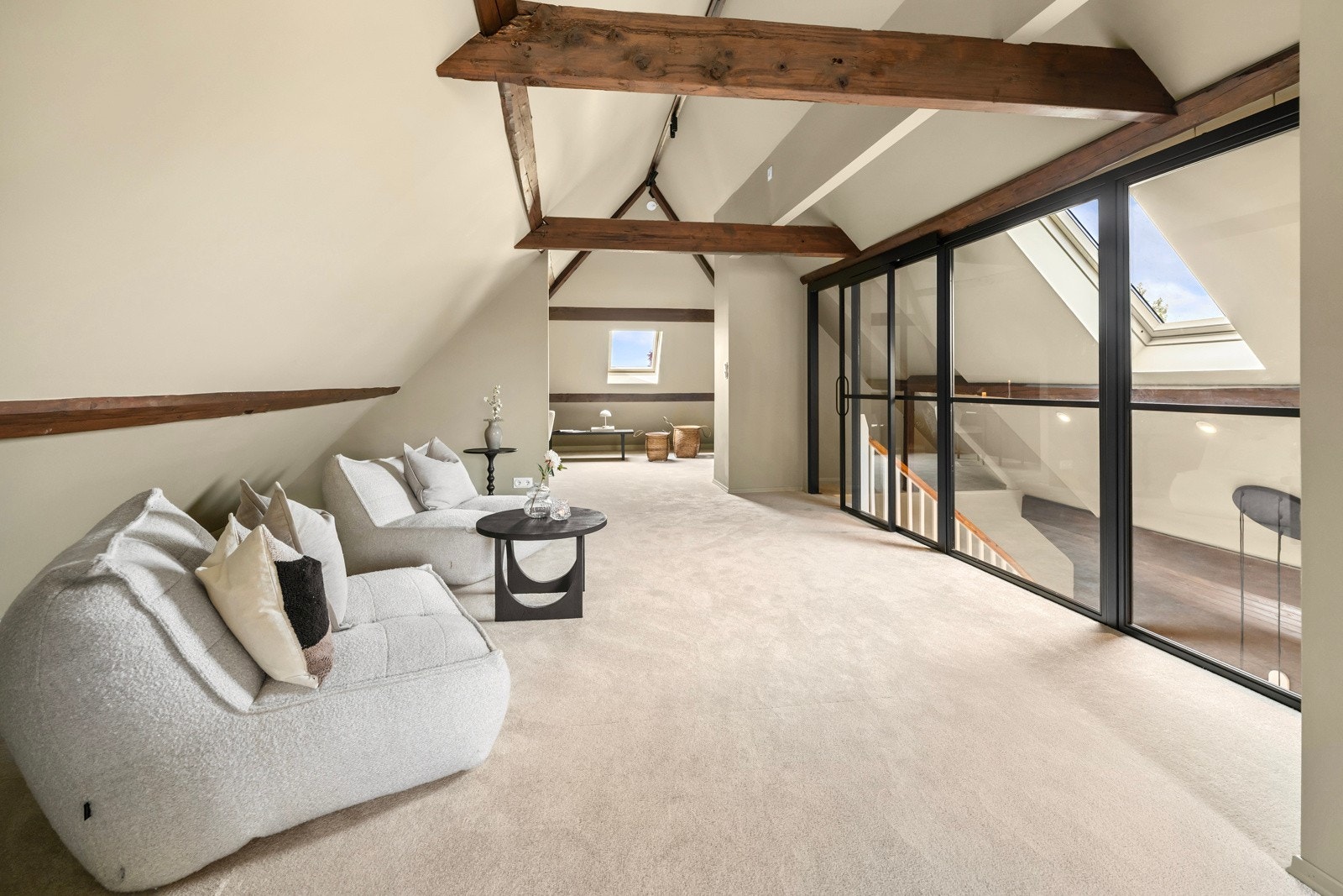 Trappegangen utenfor loftstuen har mønet skråhimling med flott takhøyde, takvindu, downlights og detaljer i mørk, rustikk panel og bjelker. Galleribilde