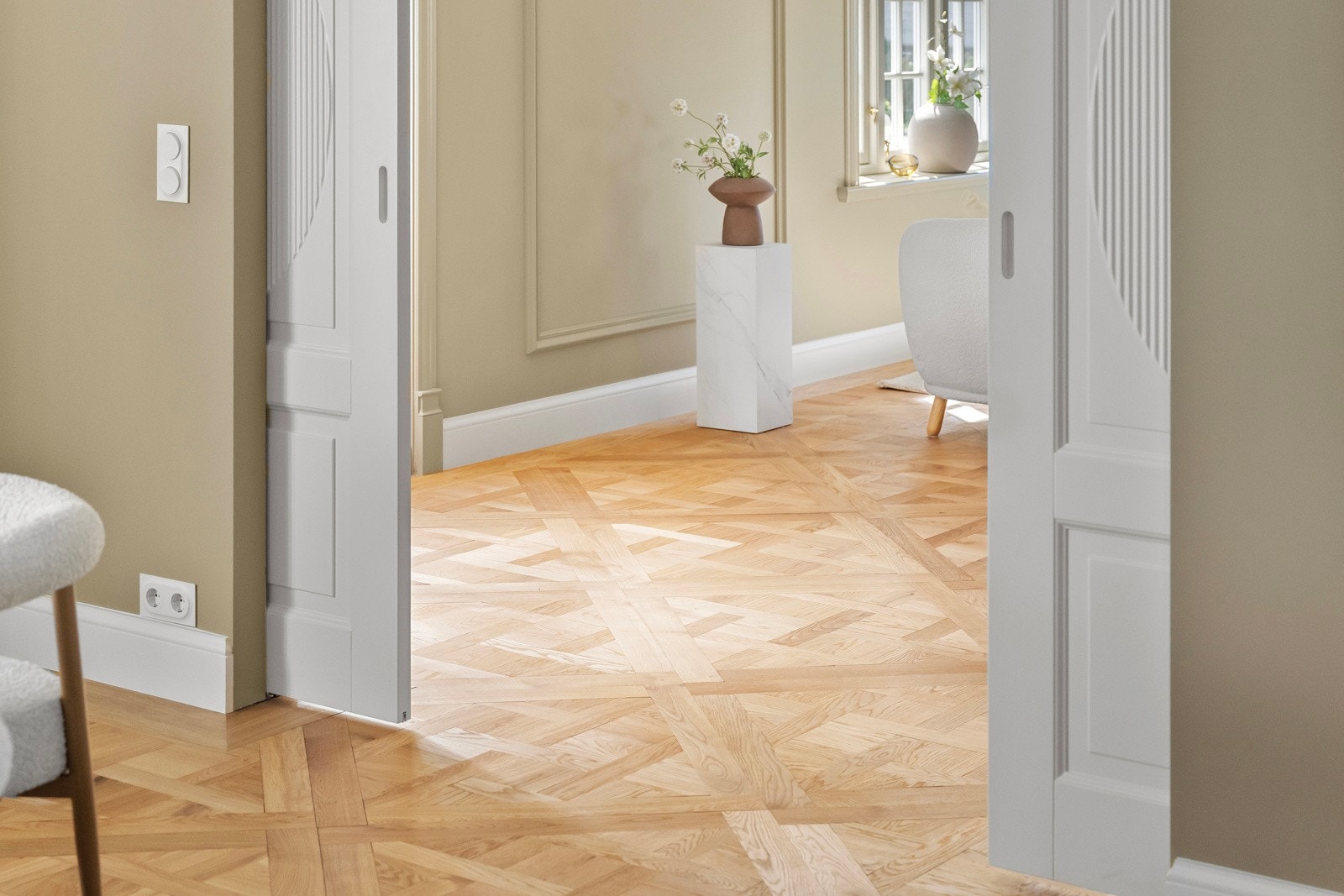 Stuen har vakker mønsterparkett på gulvet, glatte veggflater med profildekor, samt glatt, hvitmalt himling med indirekte stemningsbelysning, stilren stukkatur og to takrosetter med lampepunkt. Galleribilde