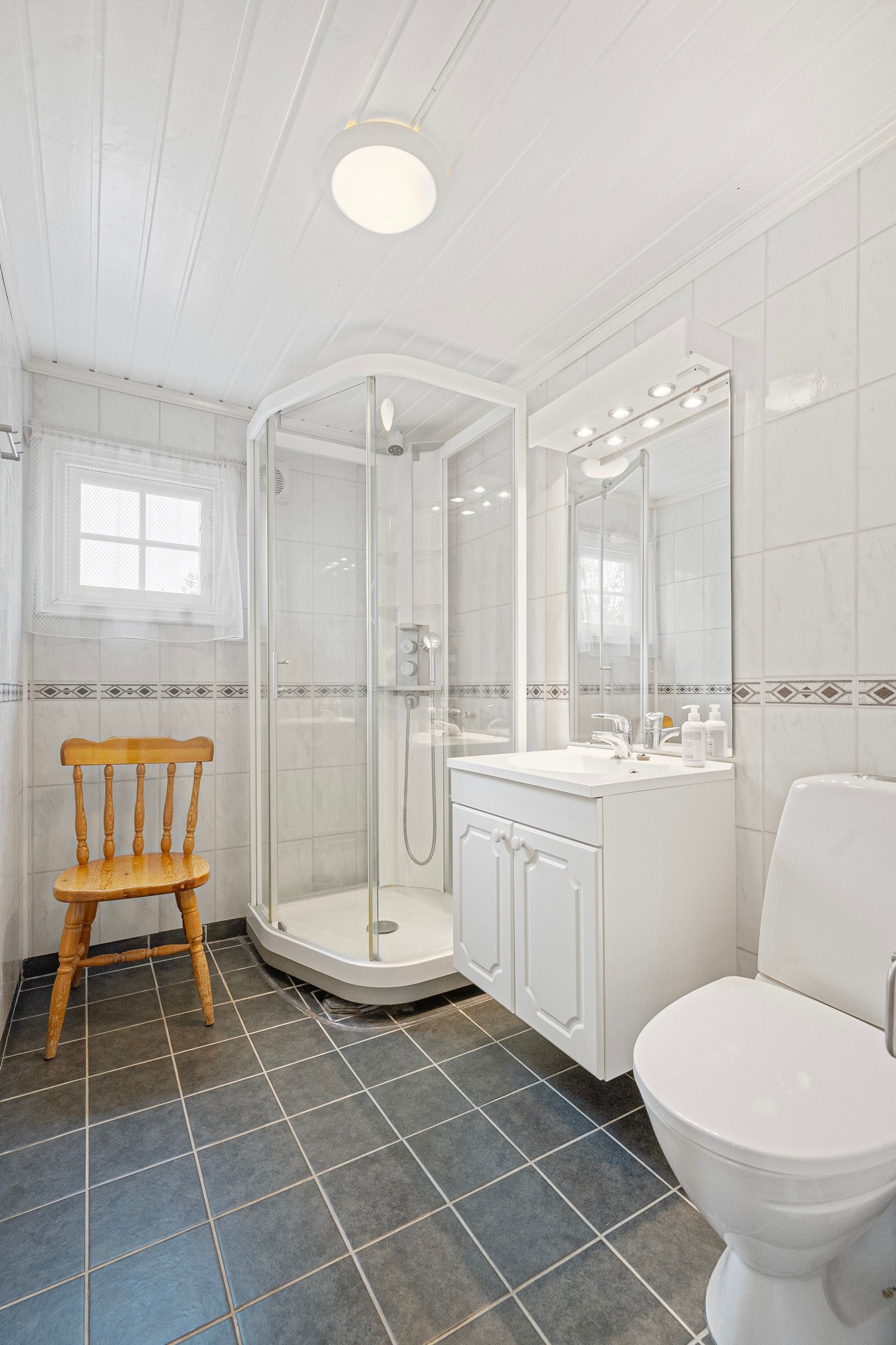 Bad har overflater på gulv av fliser og vegger har overflater av baderomsplater. Galleribilde