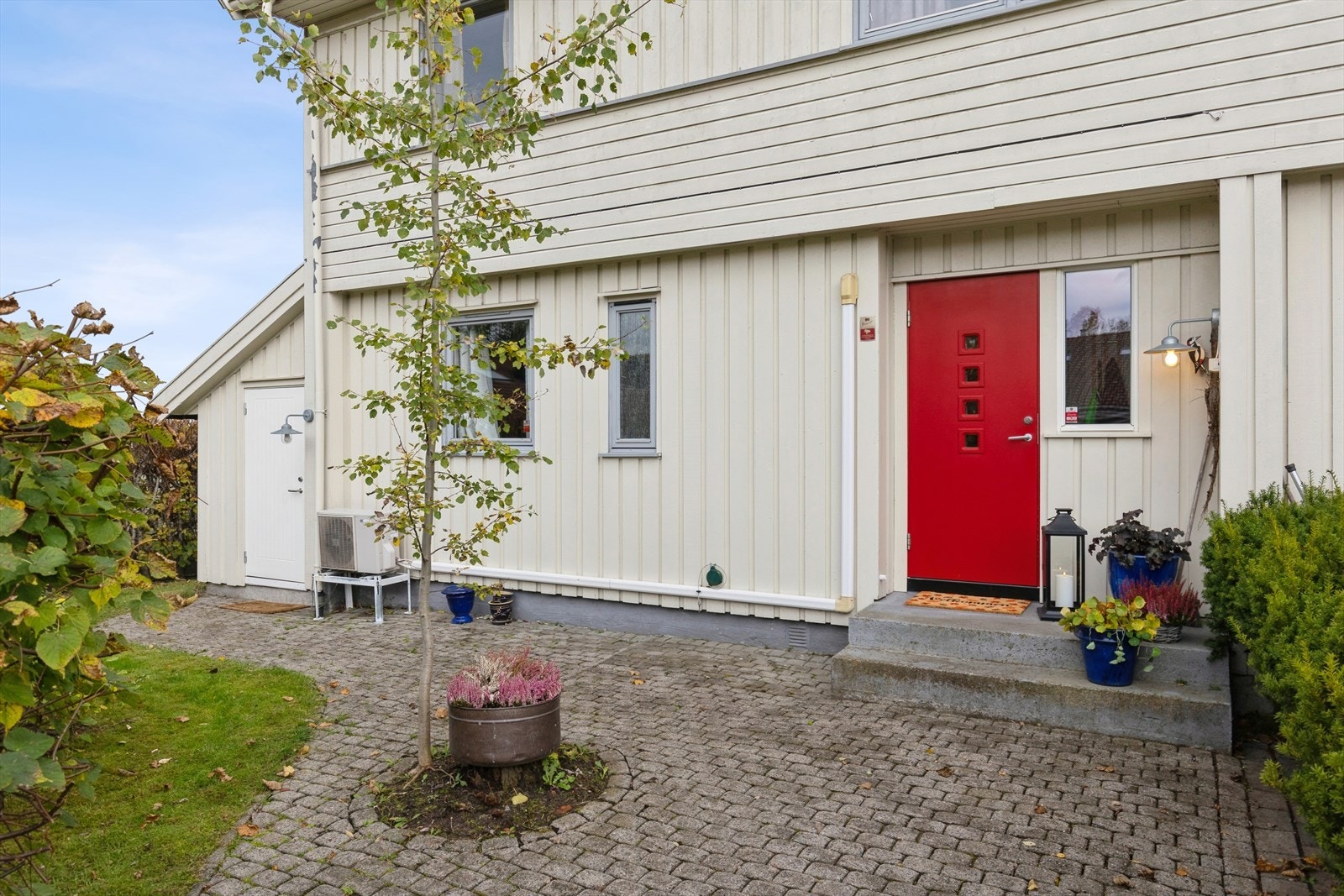 Pent opparbeidet uteområde med belegningsstein ved inngangspartiet, frodig plen og tett hekk som gir god skjerming og privatliv. Galleribilde