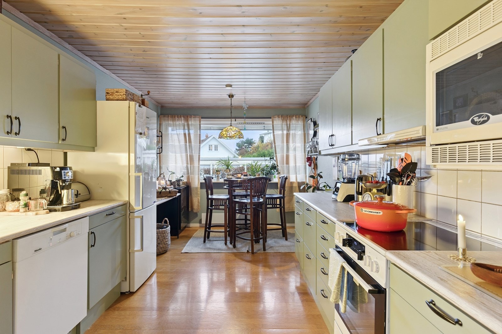 Pent kjøkken med malte, slette fronter og laminat benkeplate. Flislagt bakvegg gir et stilrent og praktisk uttrykk. Galleribilde