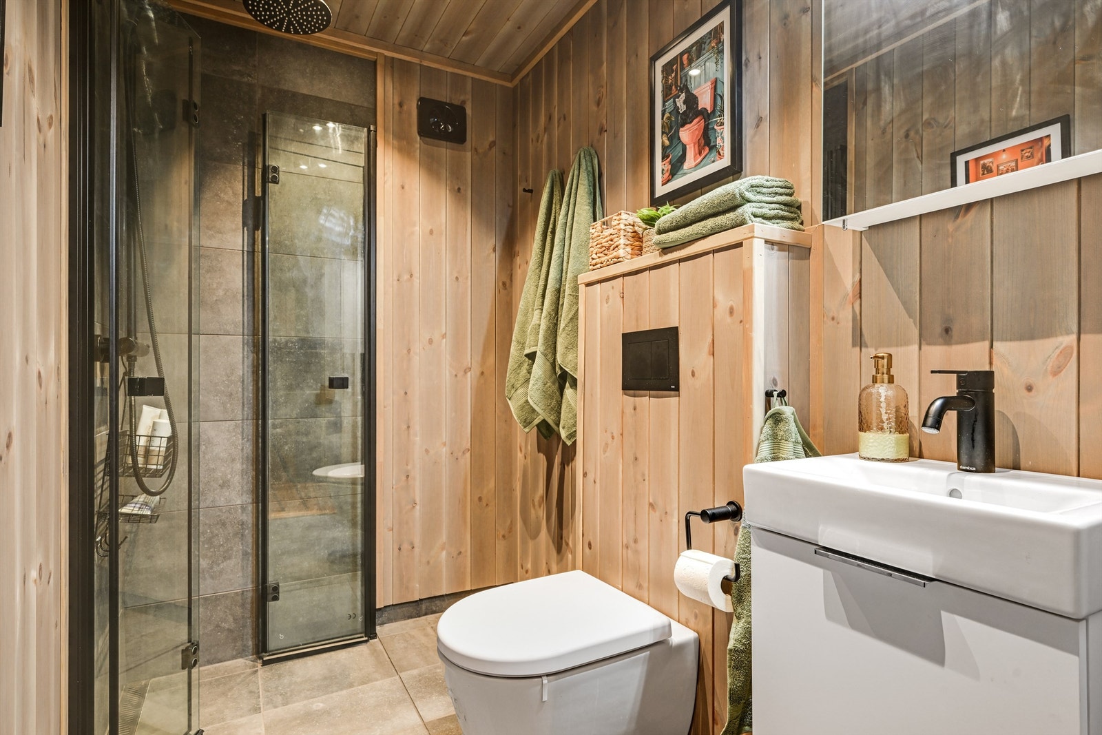 Innbydende og moderne bad innredet med dusjhjørne, wc, servant og speil. Galleribilde