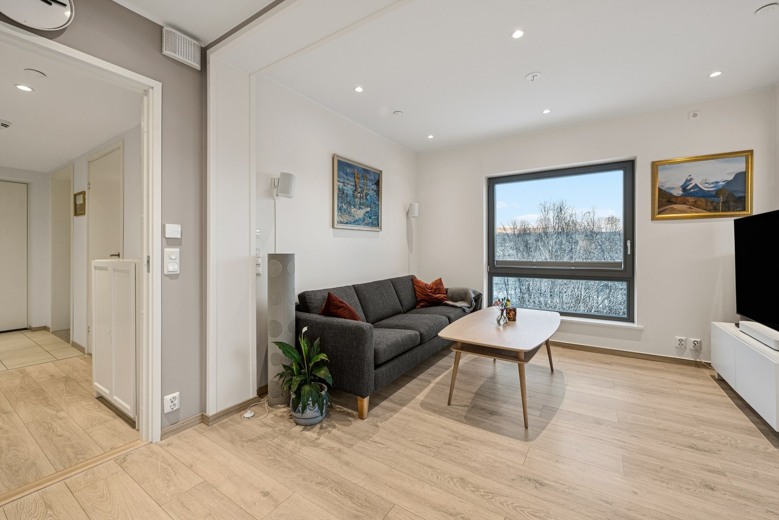 Lys og innbydende stue med moderne laminatgulv og slette malte vegger. Galleribilde