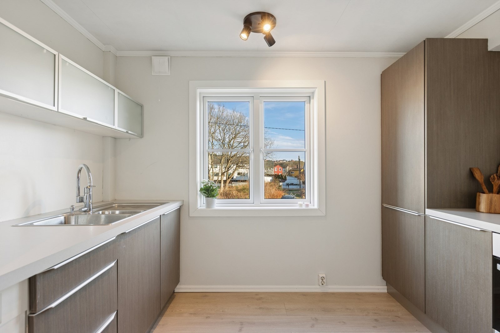 Kjøkkenet er skjermet fra stuen, og har en moderne innredning med glatte fronter. Det rause vinduet gir godt med lysinnslipp. Galleribilde