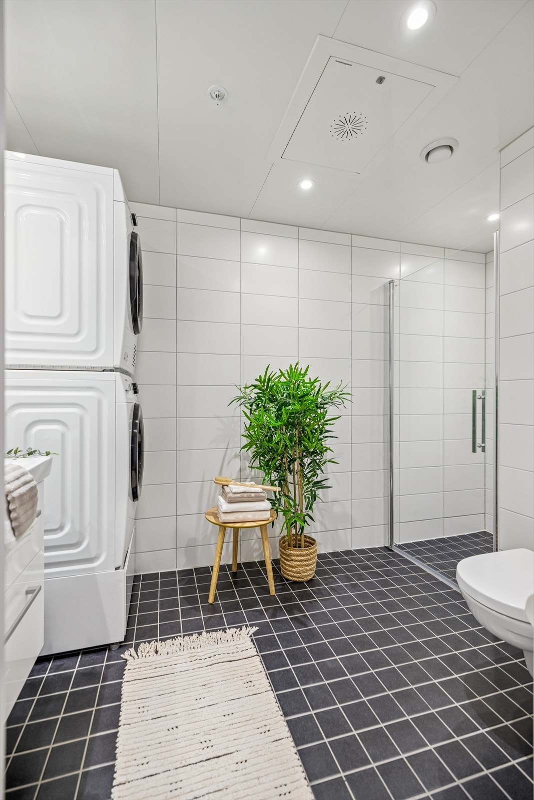 Badet er helfliset med mørke gulvfliser og hvite veggfliser. Galleribilde