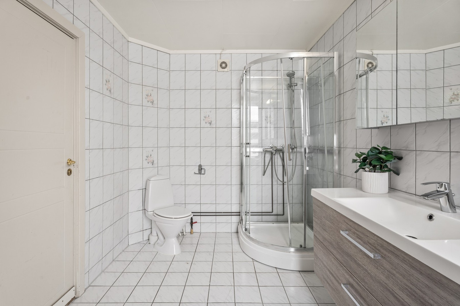 Badet er innredet med dusj, toalett og servant med oppbevaring. Galleribilde