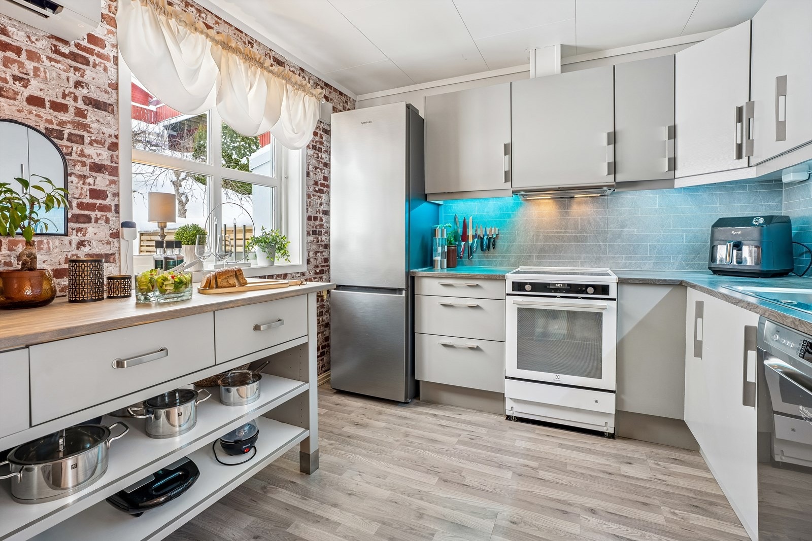 Kjøkkenet har en stilig teglsteinsvegg og rikelig med både skap- og benkeplass. Galleribilde