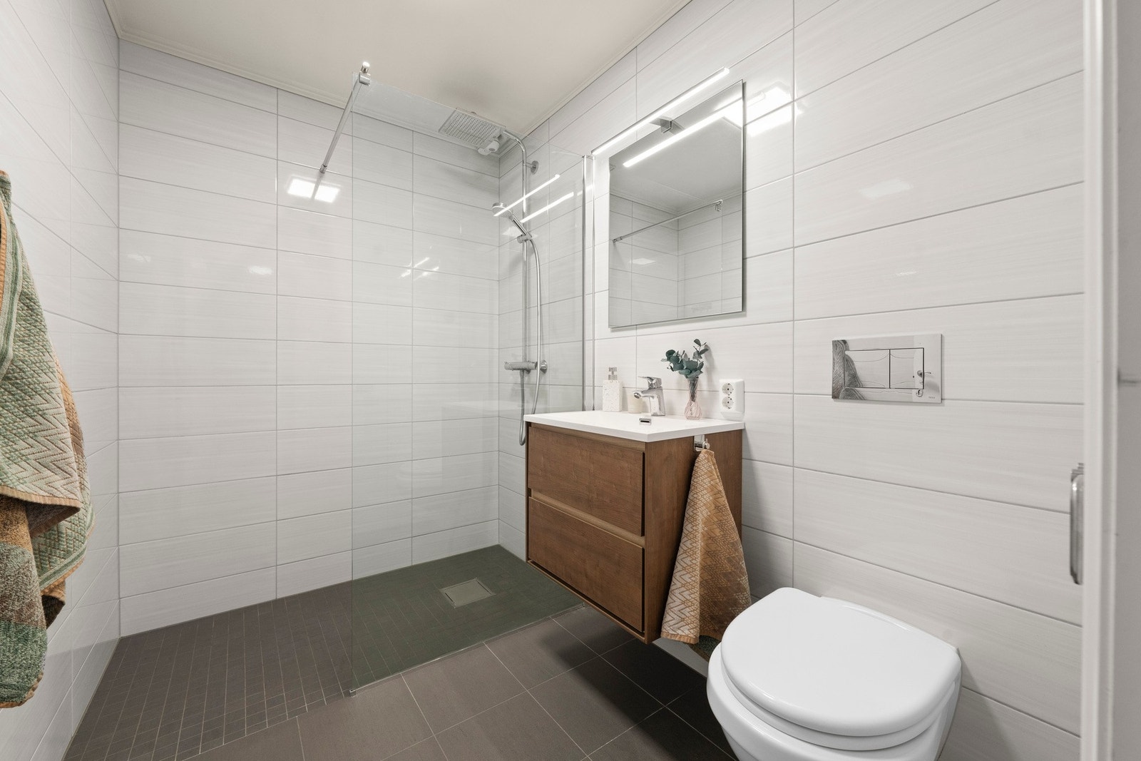 Stilrent bad i 2. etasje totalrenovert i 2018 med helflisede overflater, veggmontert toalett og romslig dusjnisje med glassvegger. Galleribilde