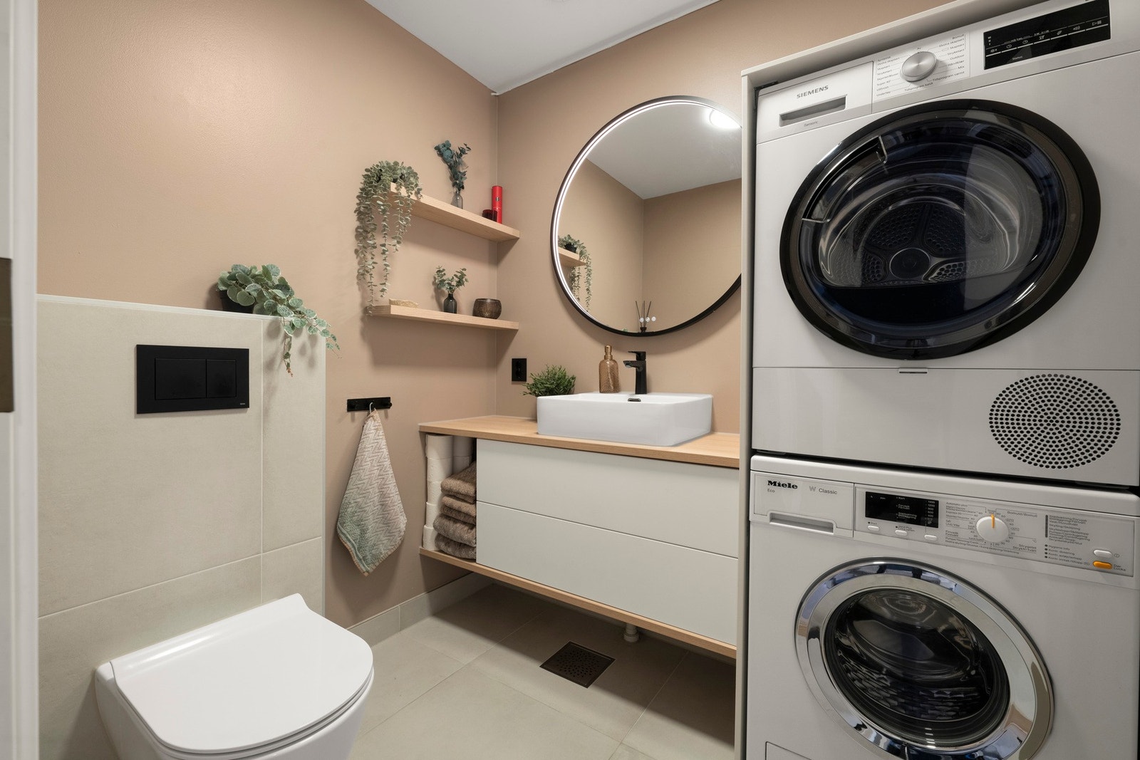 Moderne og gjennomført toalett og vaskerom renovert i 2023 med flislagt gulv, delikate fargetoner og praktisk innredning med opplegg for vaskemaskin og tørketrommel. Galleribilde