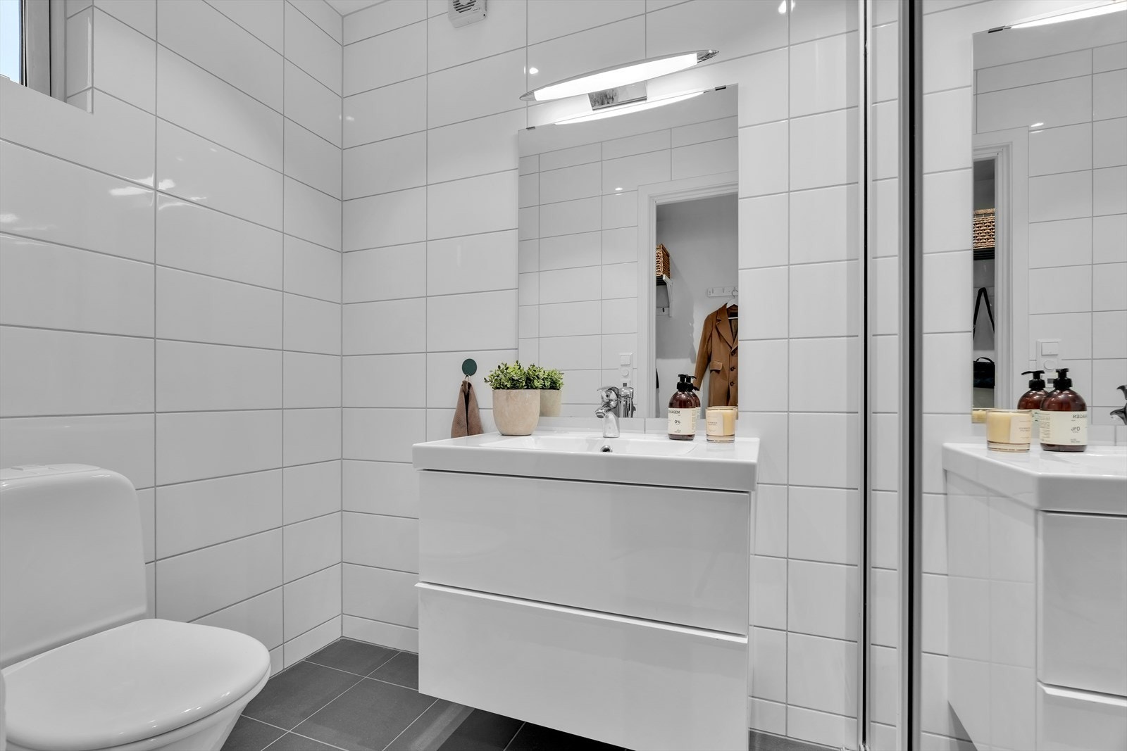 Bad i 1. etasje: Dette er et funksjonelt og stilrent vaskerom med fliser på gulvet. Rommet inneholder innredning, speil og toalett. Galleribilde