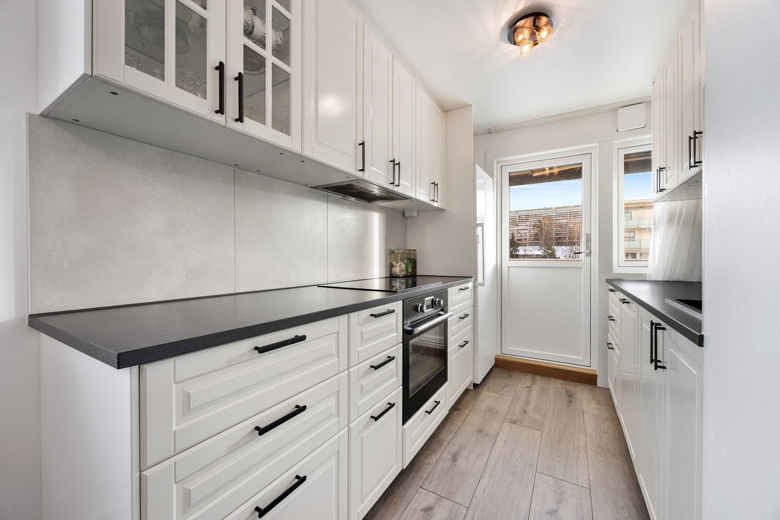 Kjøkkeninnredningen har profilerte fronter og moderne, sorte håndtak. Galleribilde