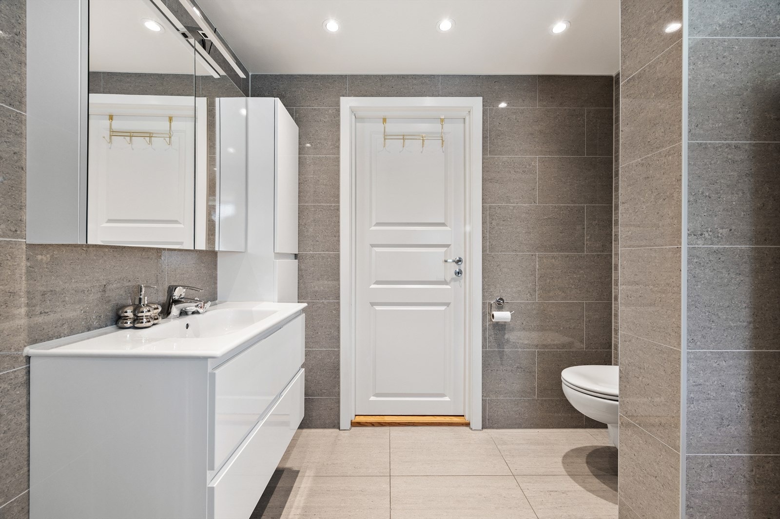 Baderomsinnredning med heldekkende servant, toalett og speilskap med belysning. Galleribilde