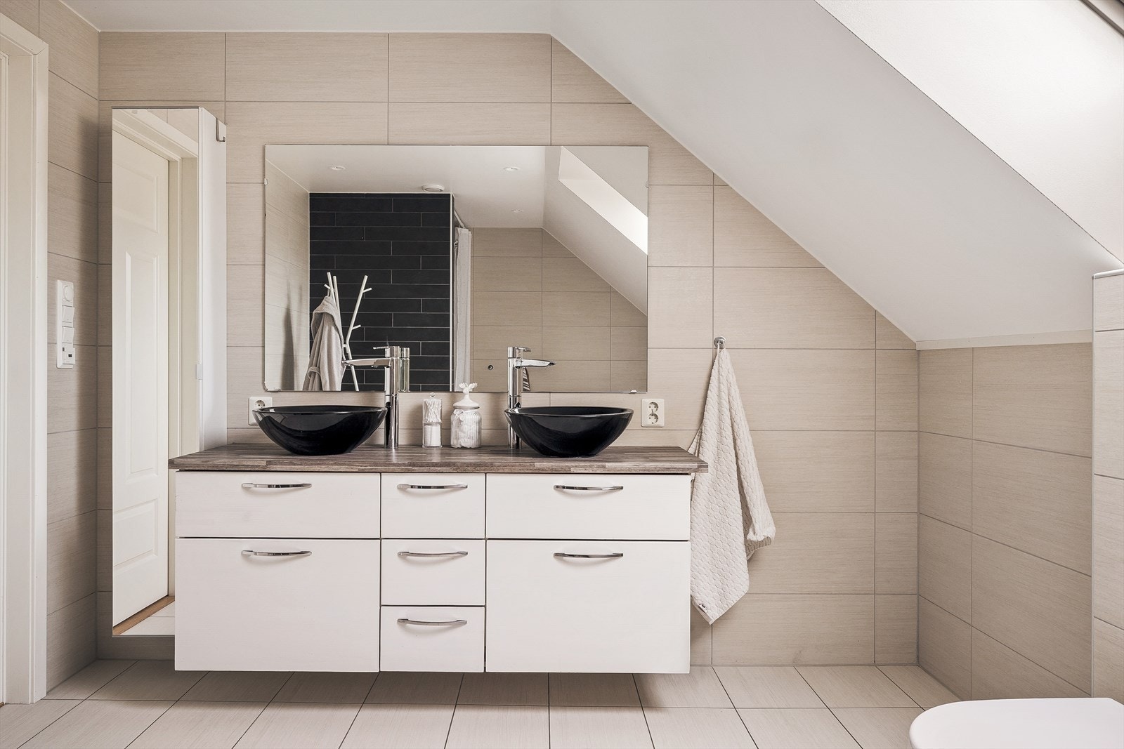 Badet er godt utstyrt med moderne baderomsmøbler som et praktisk dobbeltservant med møblement og stort speil. Galleribilde