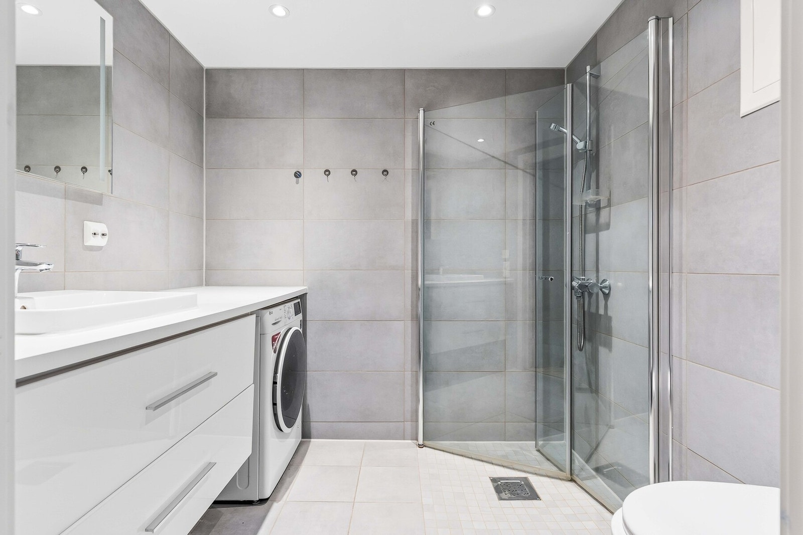 Nydelig helfliset bad med gulvvarme, opplegg for vaskemaskin, vegghengt toalett, servant og dusj på flis. Galleribilde