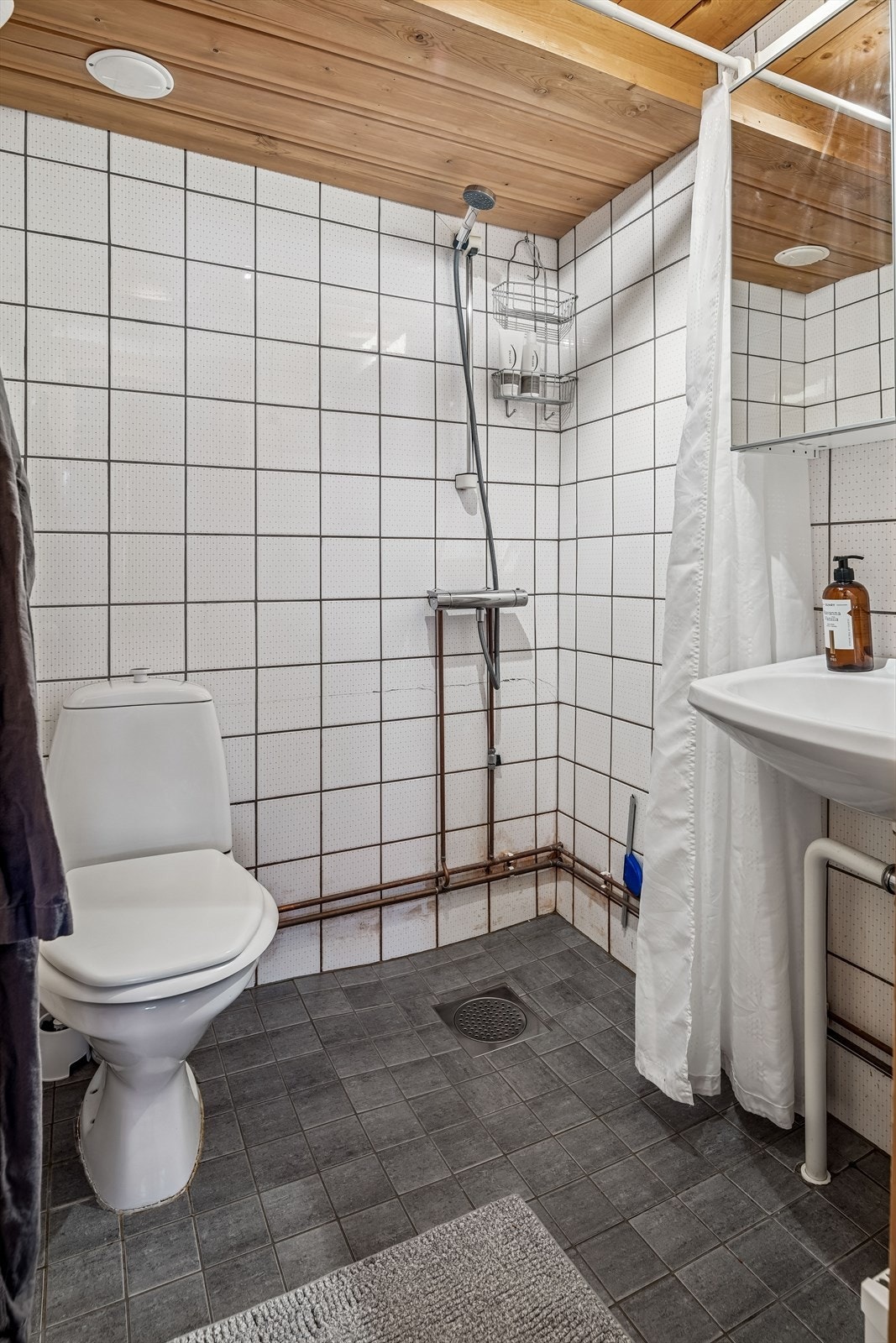 Flislagt bad fra byggeår med toalett, servant og dusjhjørne. Galleribilde