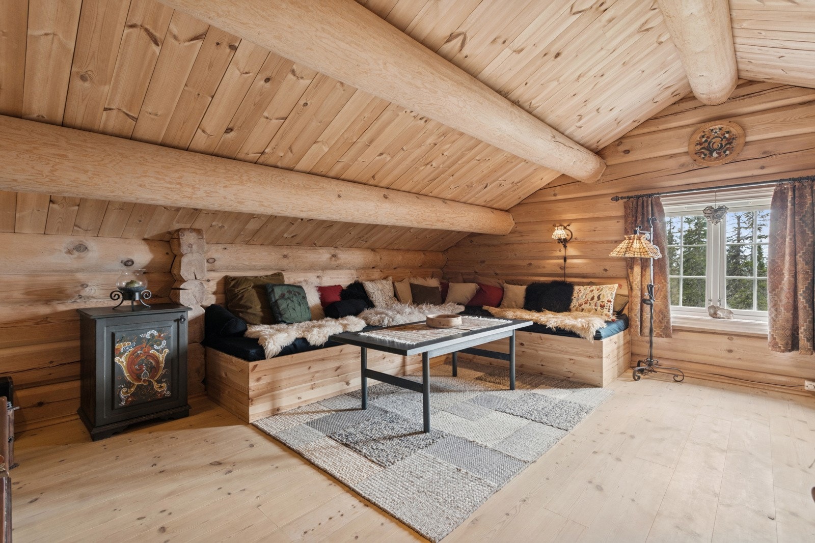 Her er det plassbygd sofagruppe som også kan benyttes til ekstra soveplasser. Merk også at de håndmalte skapene bidrar til et helhetlig og fint preg i hytta. Galleribilde