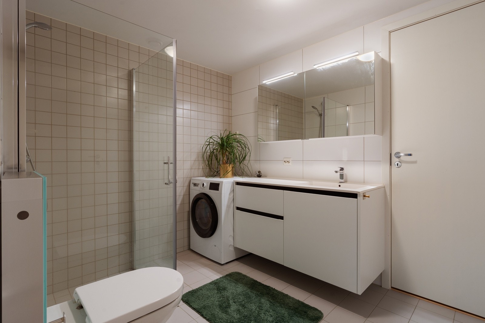 Moderne og flislagt bad med vegghengt wc og opplegg for vaskemaskin og plass for tørketrommel.