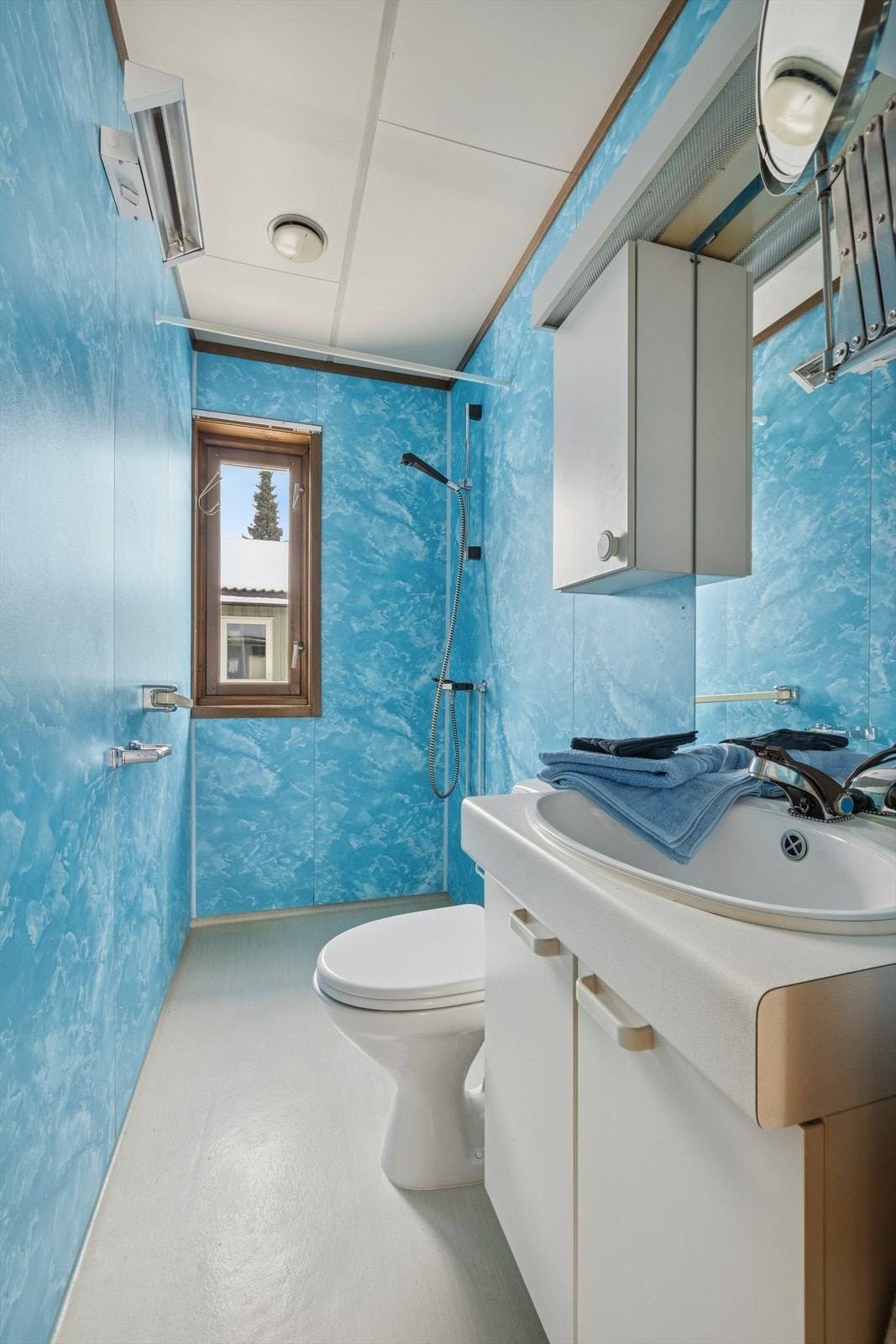 Badet er utstyrt med servantinnredning, toalett og åpen dusjløsning. Galleribilde