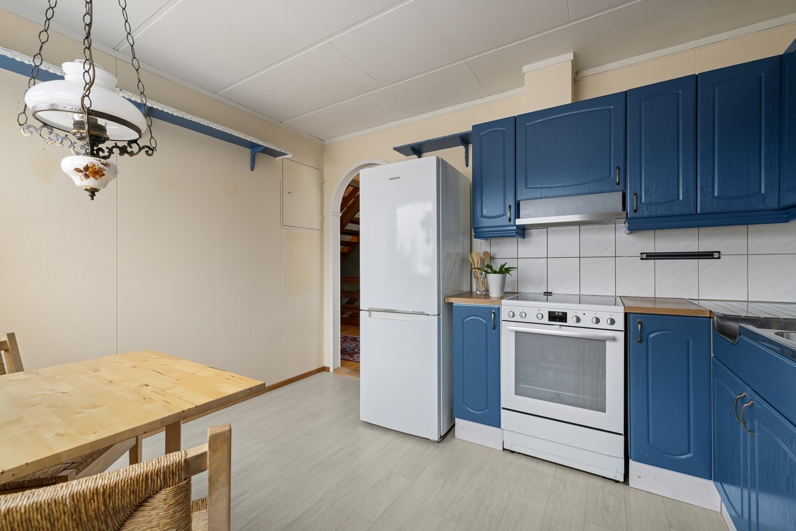 Kjøkken med praktisk innredning med malte, profilerte fronter og laminat benkeplate med dobbel oppvaskkum. Galleribilde