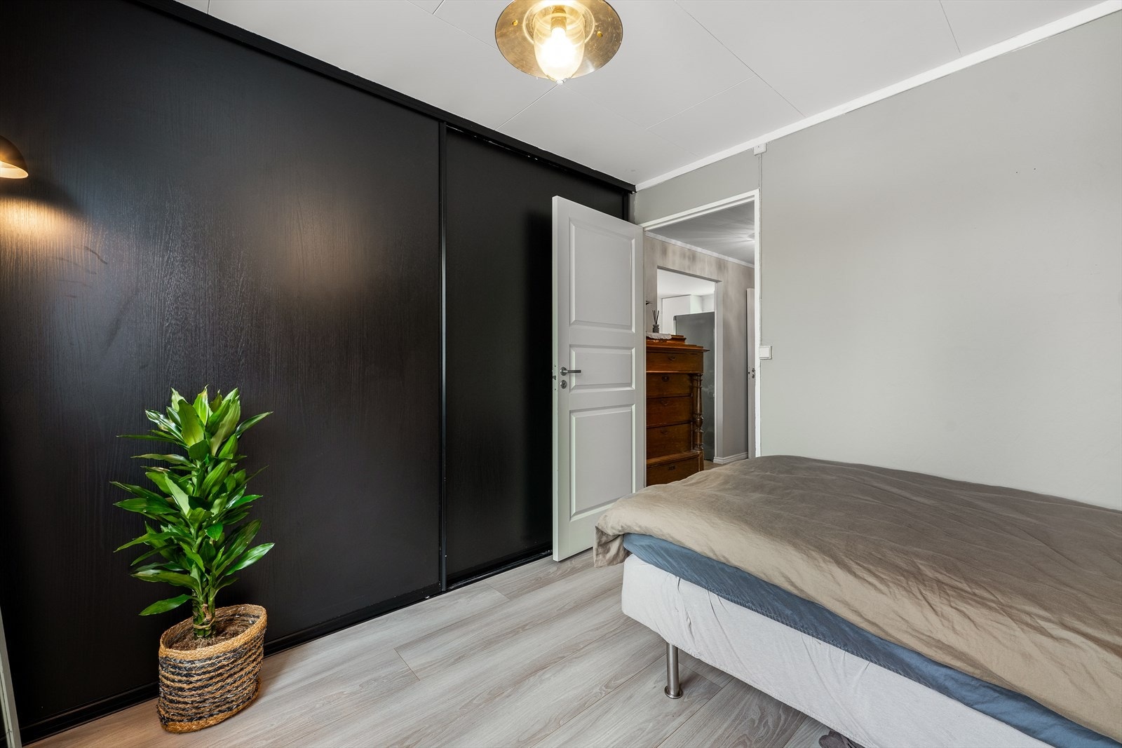 Skyvedørsgarderobe gir effektiv oppbevaring i soverommet, som har laminatgulv. Galleribilde