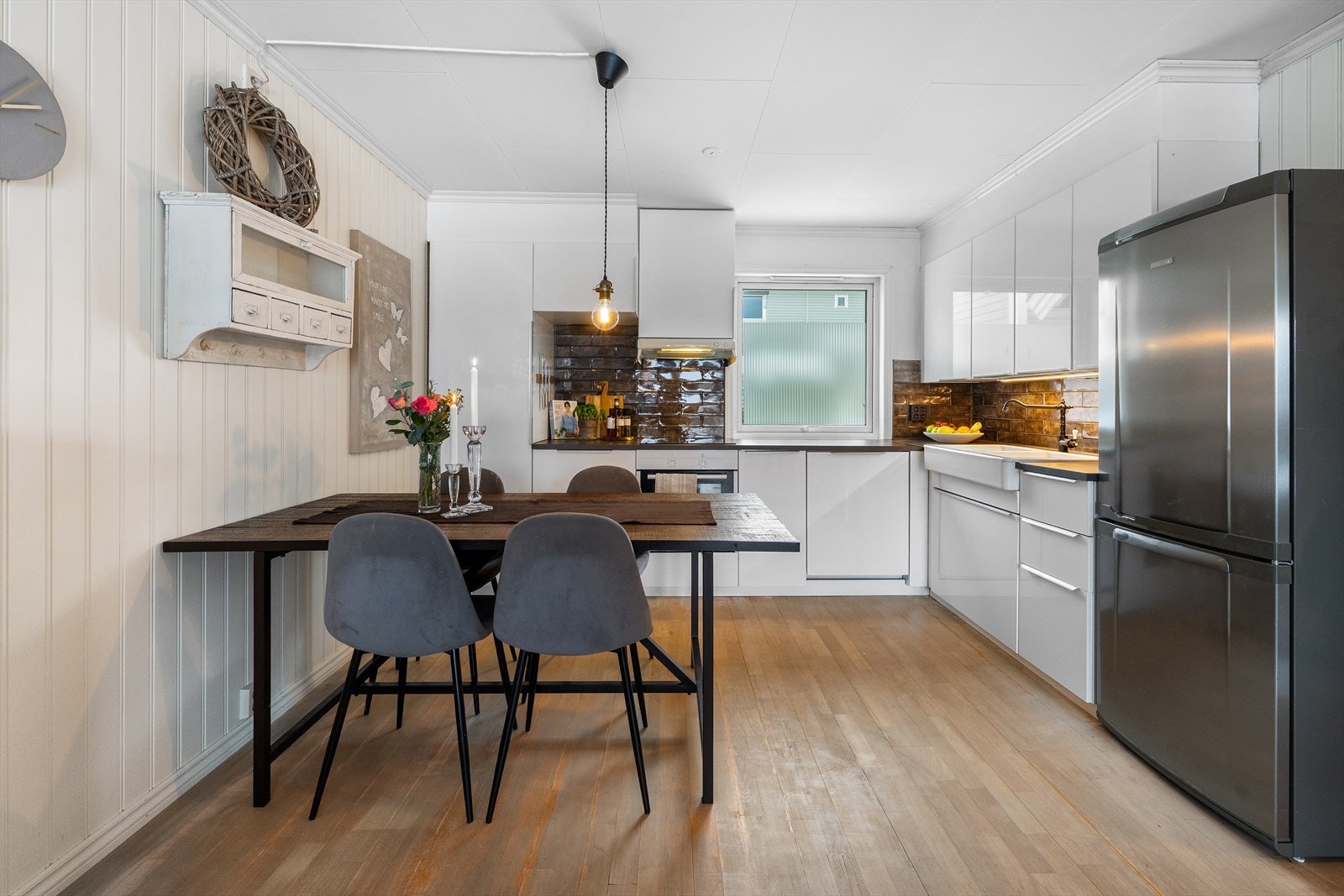 Kjøkkenet har en innredning med glatte fronter og laminert benkeplate, med fliser på veggen over benken. Galleribilde